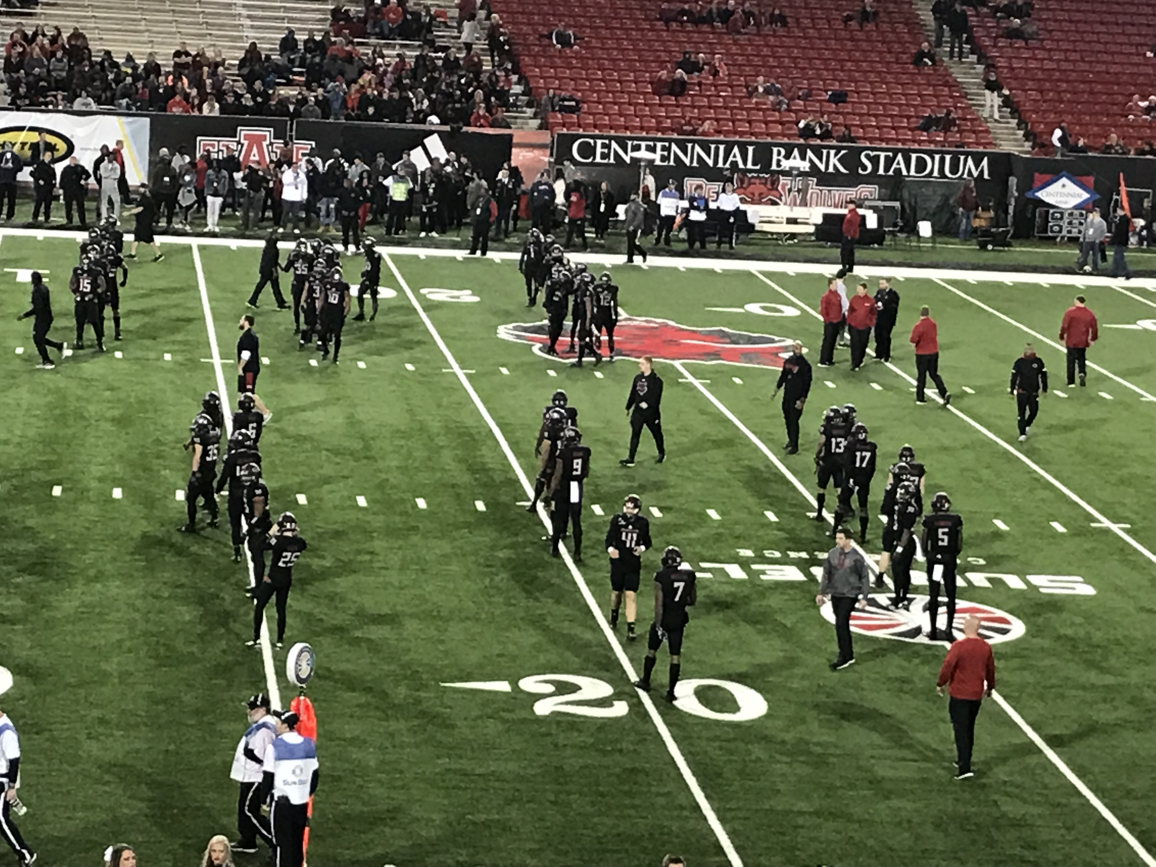 Football players warm up on the field at Centennial Bank Stadium before a game.