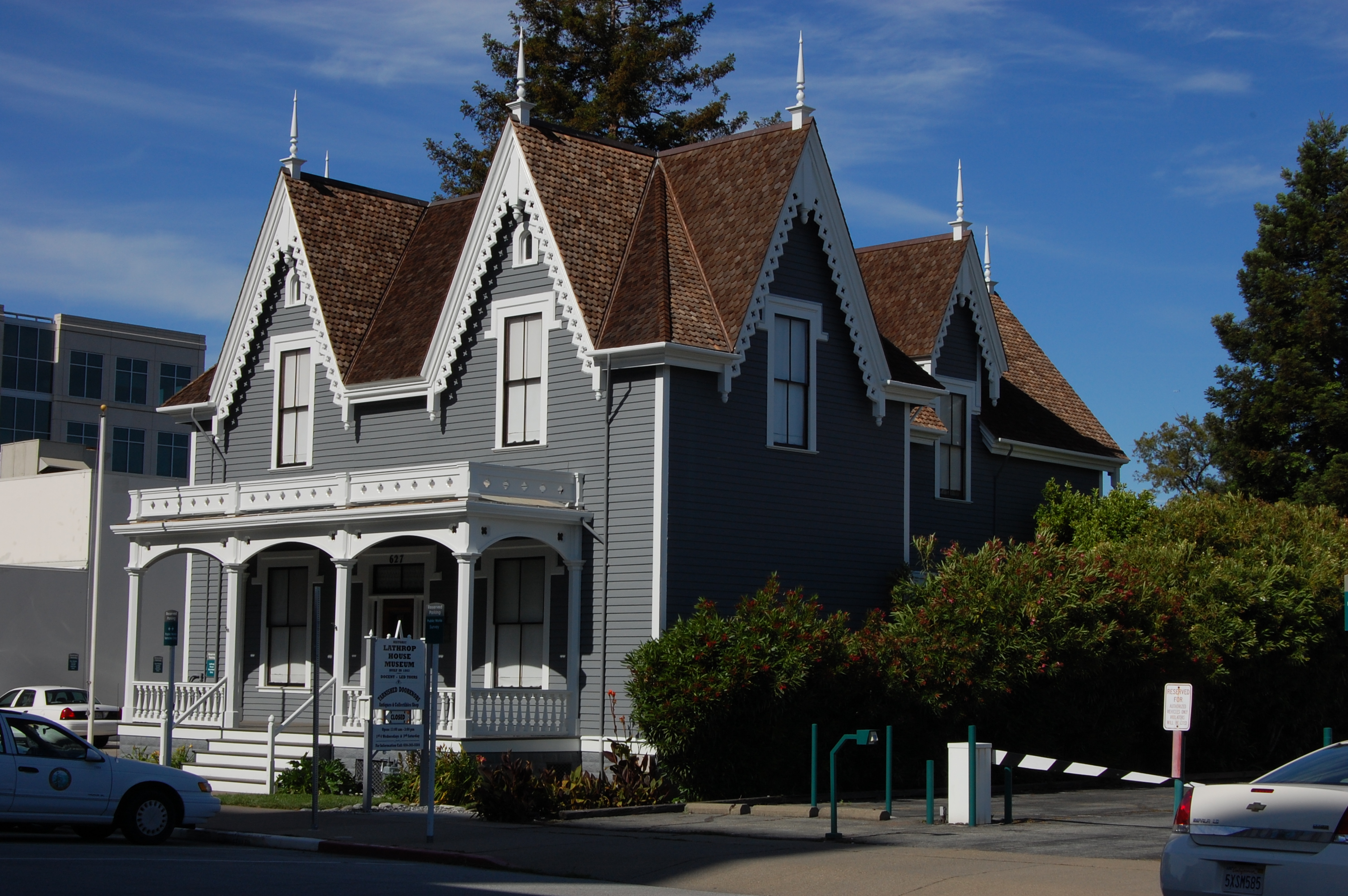 A gray Steamboat Gothic Victorian house with ornate white trim, steep gabled roofs, and a front porch with columns.