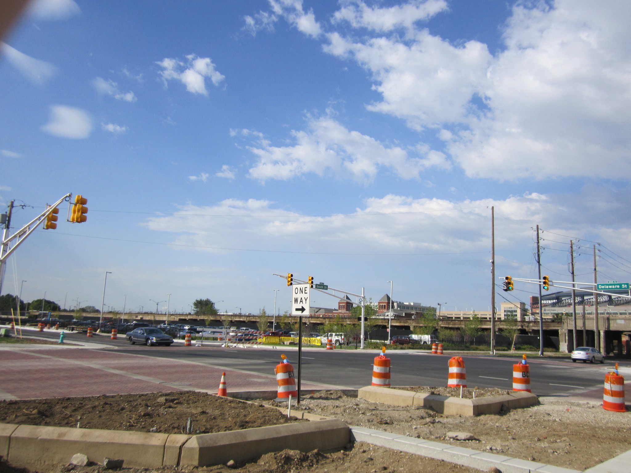 Road intersection under construction with orange barrels, cones, and a one-way sign.