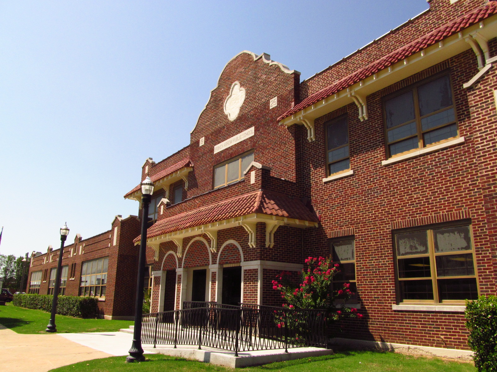 Historic red-brick school building with ornate gabled entrance and manicured lawn.