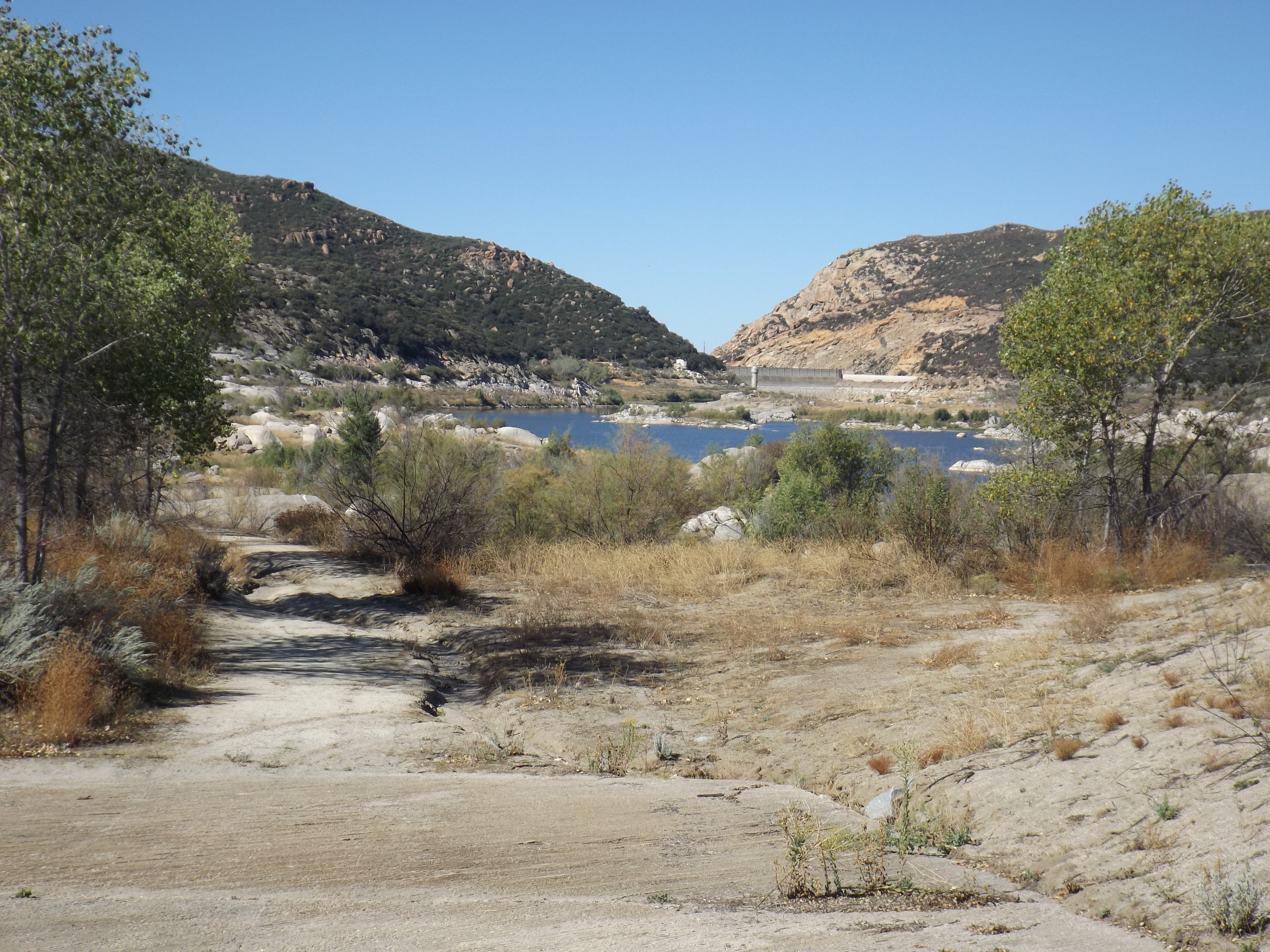 A nearly empty reservoir with an exposed boat ramp and dry rocky shoreline.