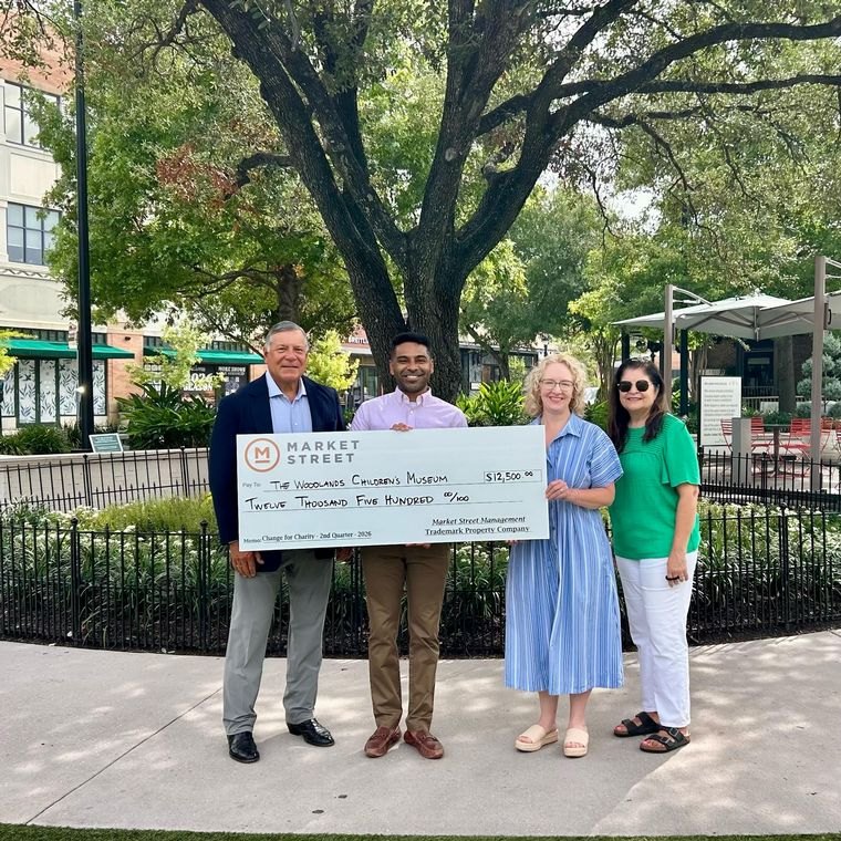 Four people hold a large ceremonial check for twelve thousand five hundred dollars outdoors.