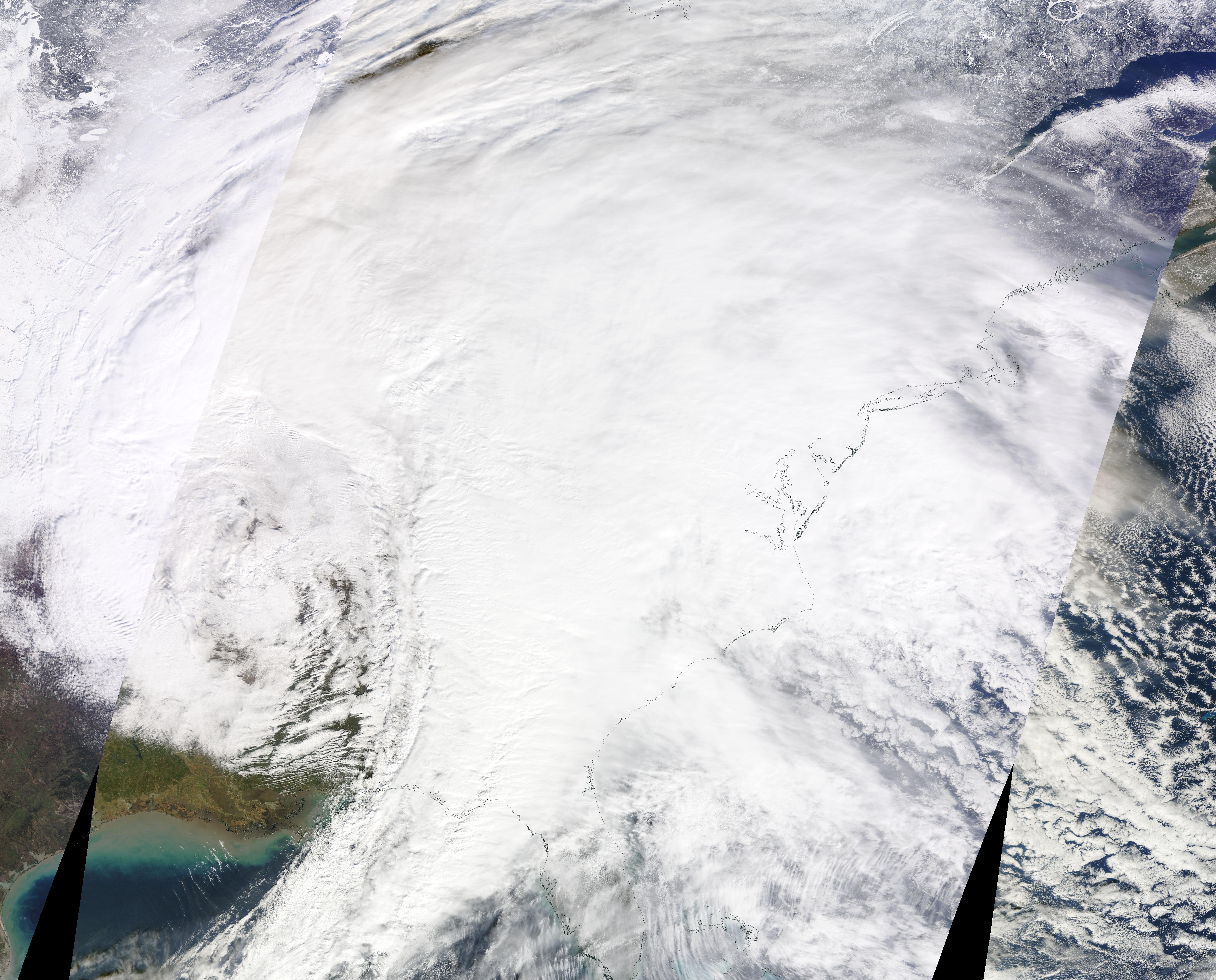Satellite view of a large swirling storm system over the eastern United States with dense cloud cover.