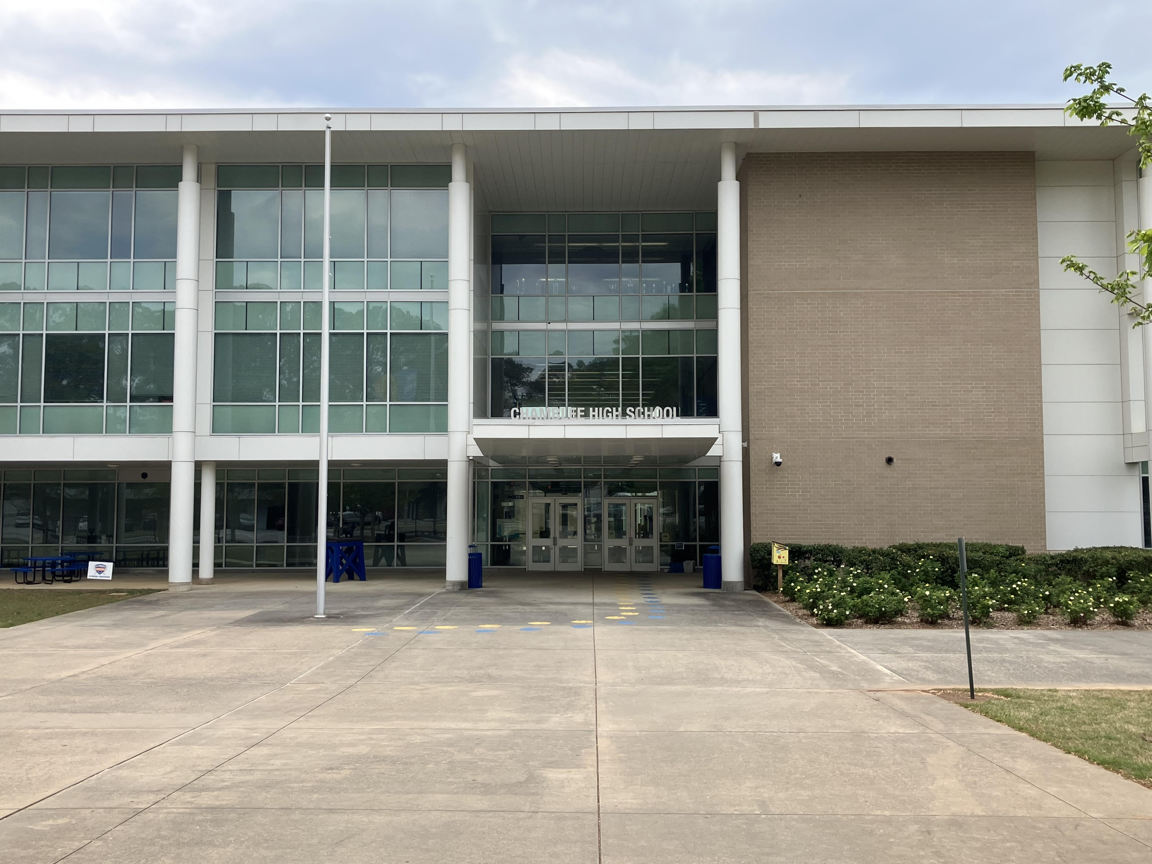 Front entrance of a modern two-story school building with large glass windows and a sign reading Chamblee High School.