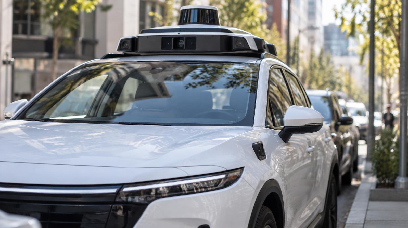 White autonomous vehicle with lidar sensor on top parked on a sunny city street.