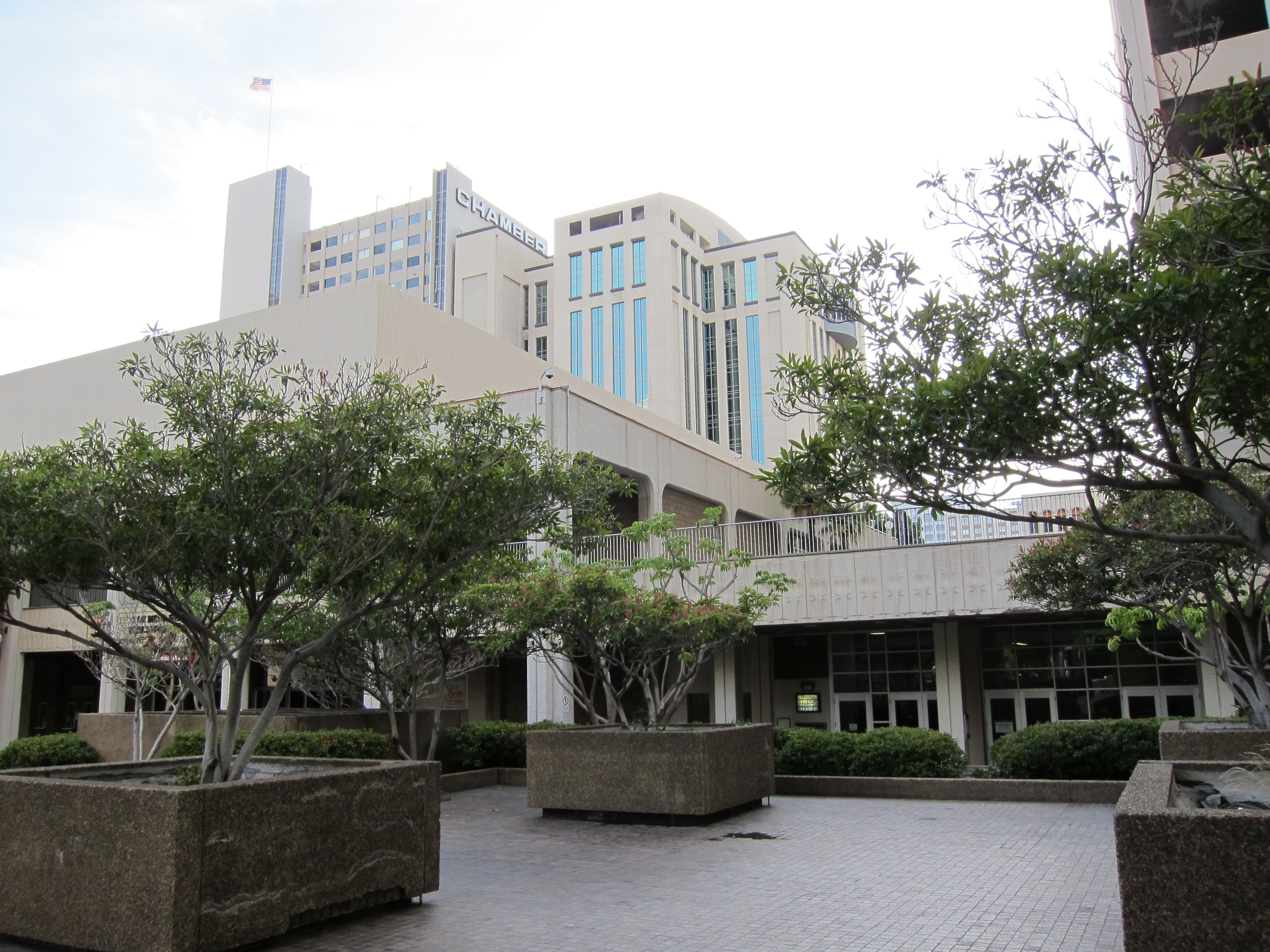 Open civic plaza with concrete planters, trees, and multi-story office buildings.