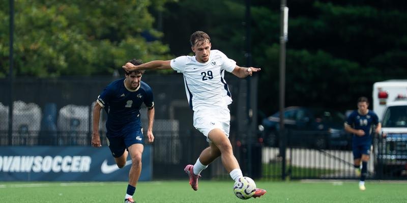 Soccer player in white uniform number 29 kicking a ball on a grass field.