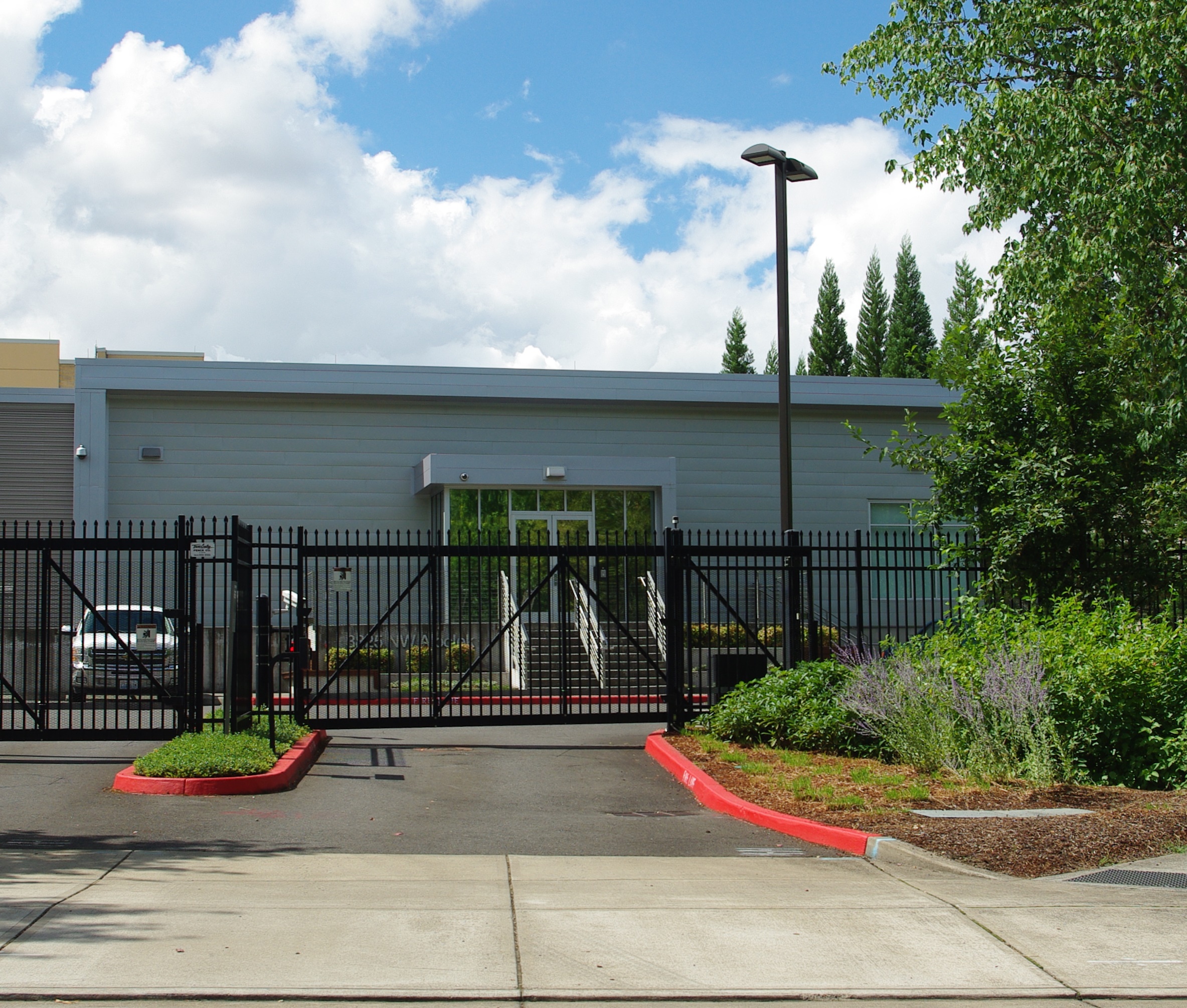 Low-profile gray data center building behind a black iron security fence and gate.
