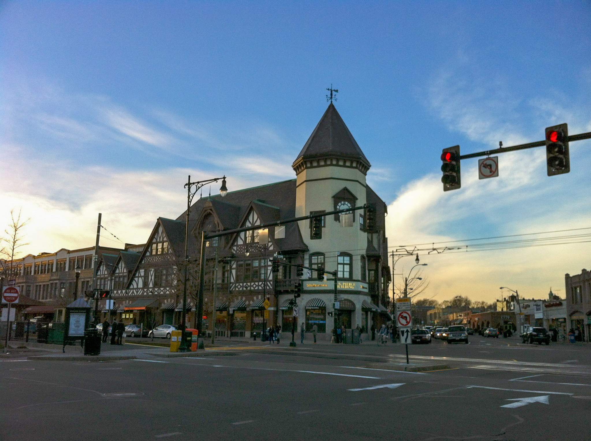 Street-level view of a busy commercial intersection with a Tudor-style corner building.