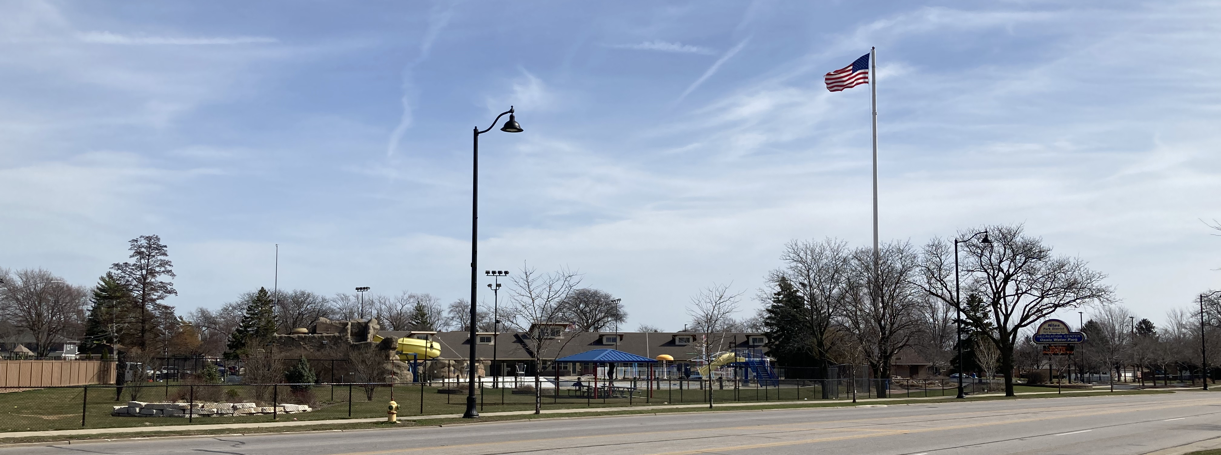 Exterior of a park district recreation center with a flagpole and playground equipment.