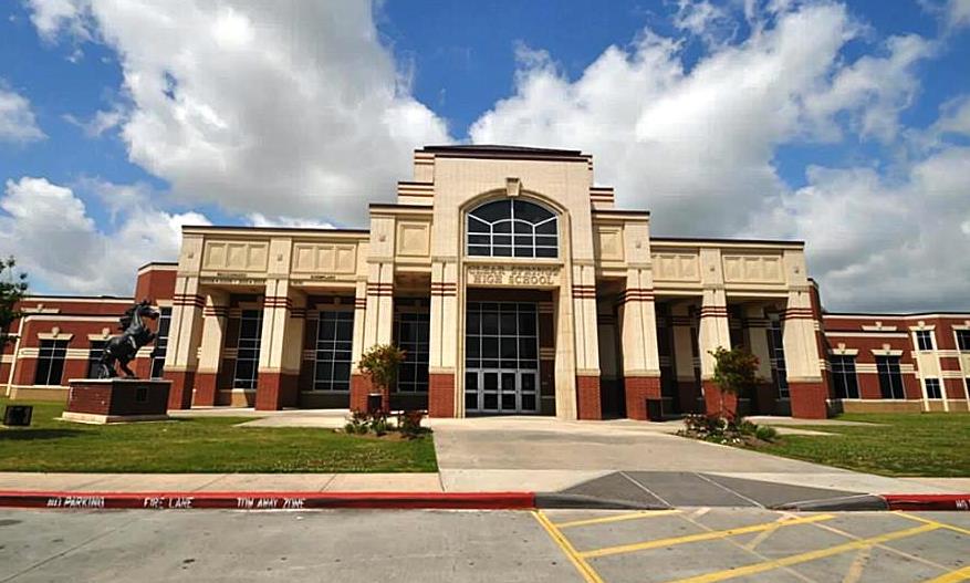 Brick front entrance of a large high school with an arched entryway and mascot statue.