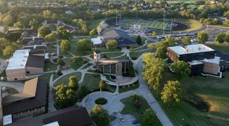 Aerial view of a university campus with brick buildings, green lawns, and a sports stadium.