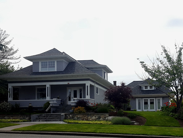 Two craftsman-style homes on a residential street, with a smaller cottage visible behind.