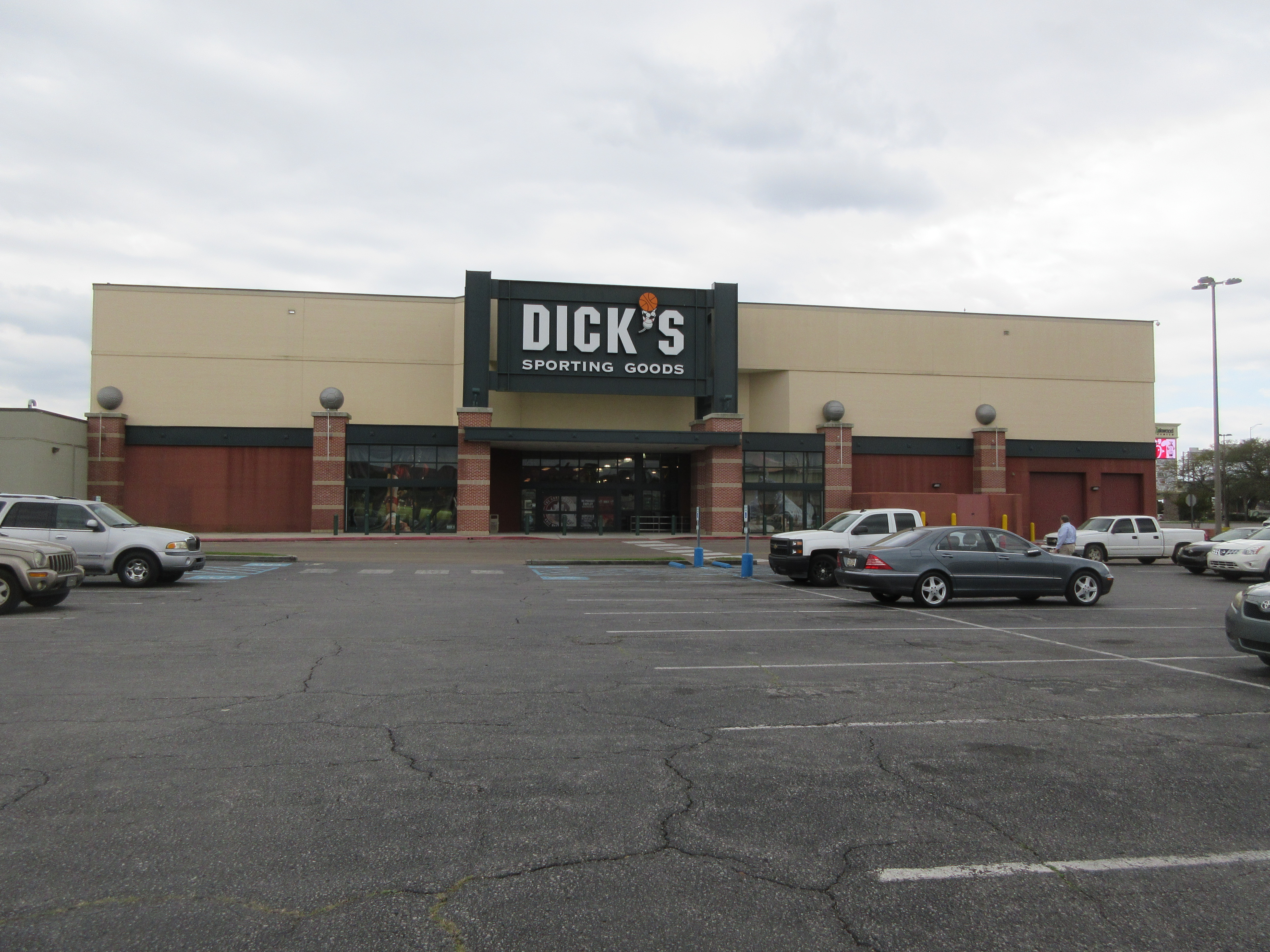 Exterior of a Dick's Sporting Goods store with parking lot and branded green signage.