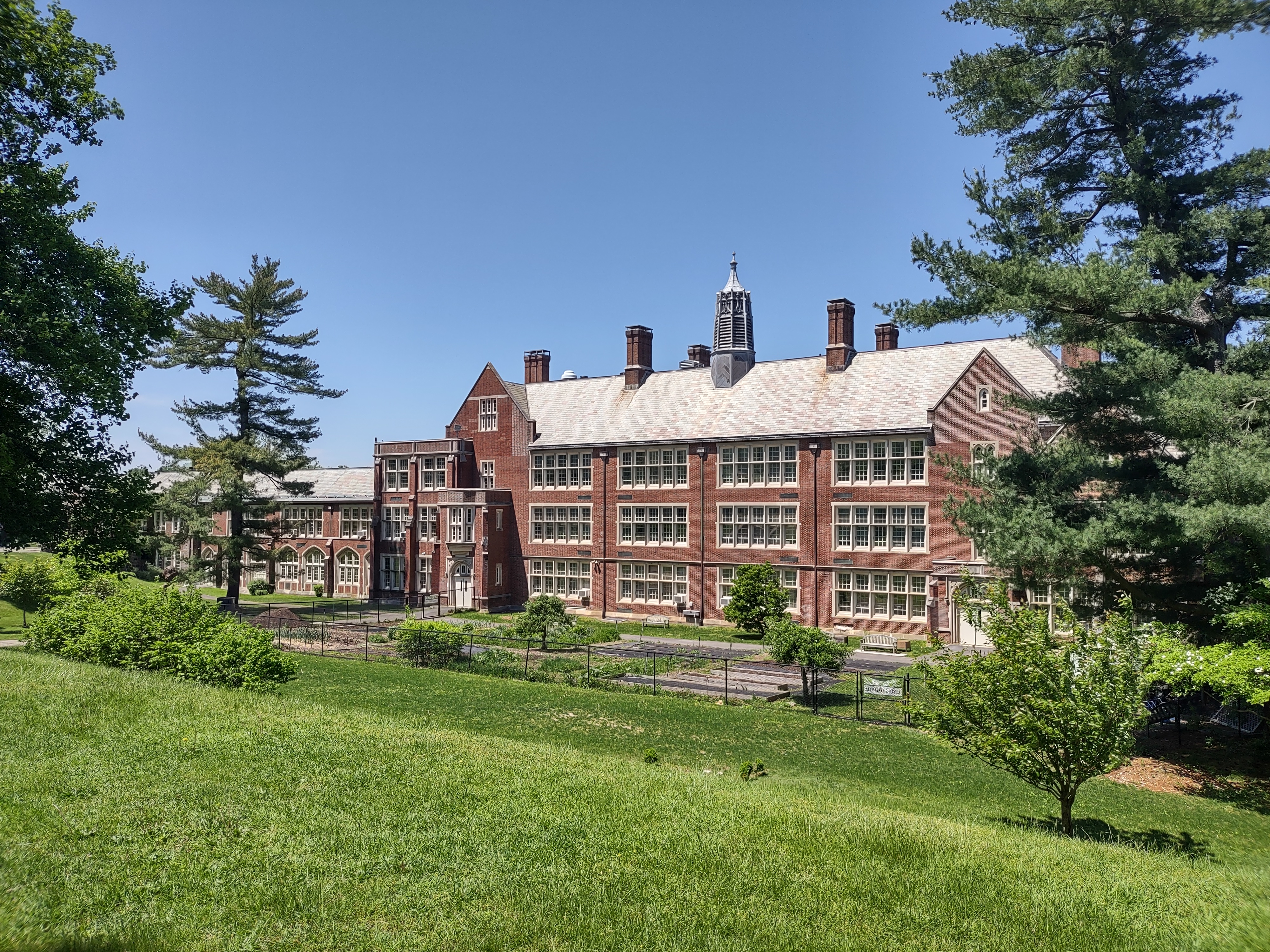Red brick high school building with Gothic architecture surrounded by green lawns and trees.