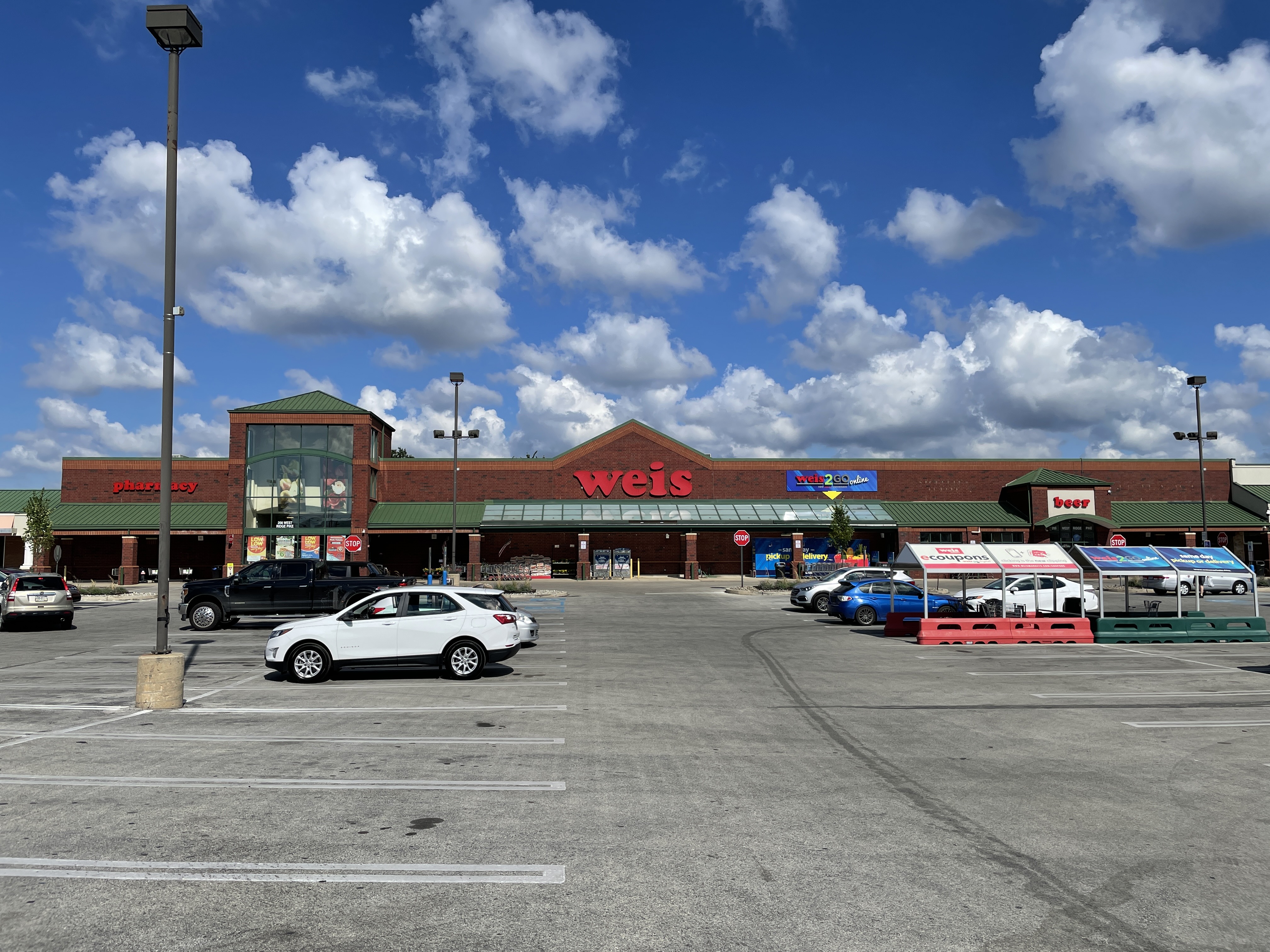 Exterior of a Weis Markets anchor store at a suburban shopping center with a large parking lot.