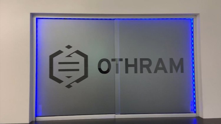 Frosted glass doors bearing the Othram company logo, framed by blue LED lighting.