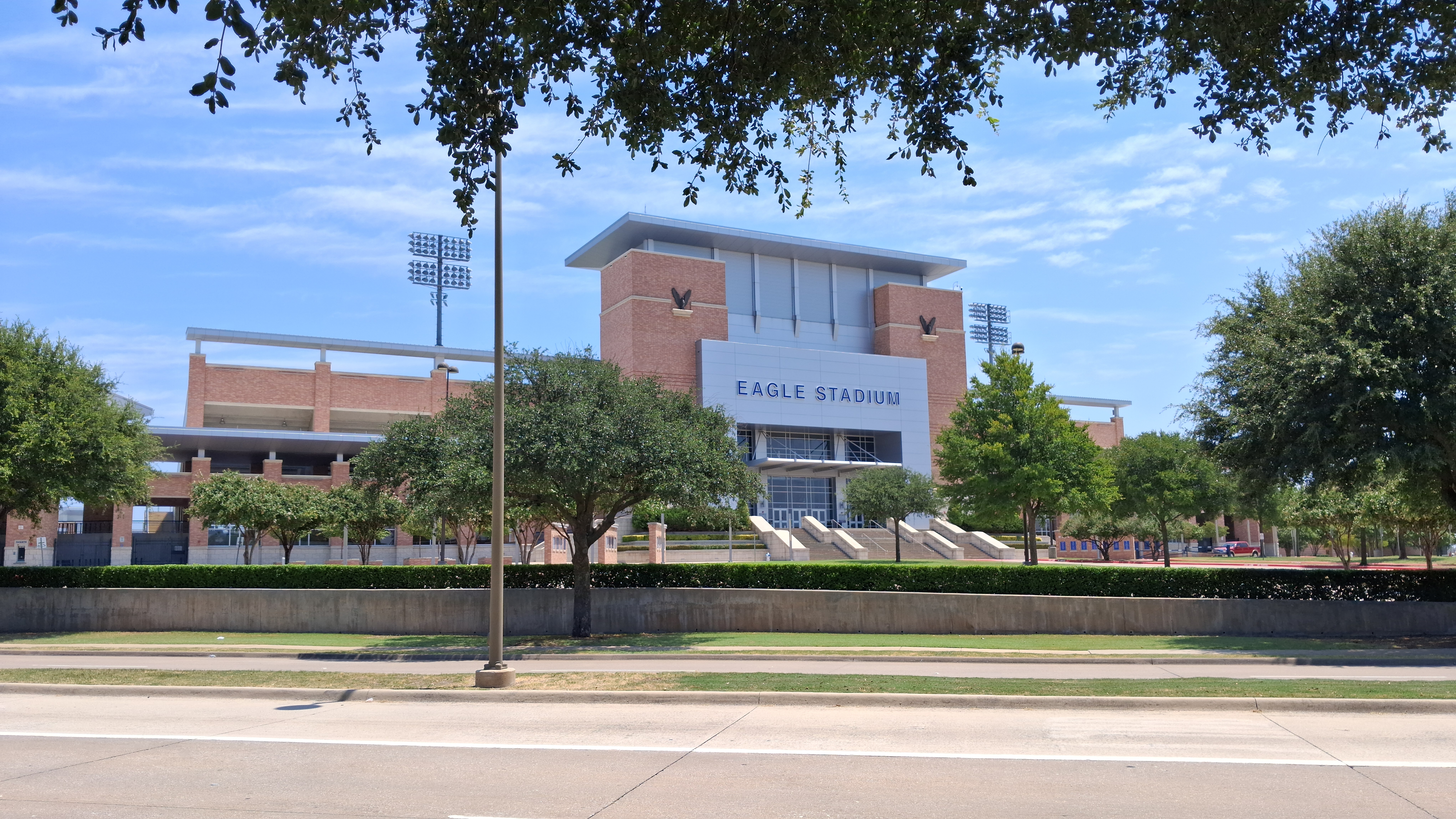 Brick stadium entrance building labeled 'Eagle Stadium' with light towers behind it.