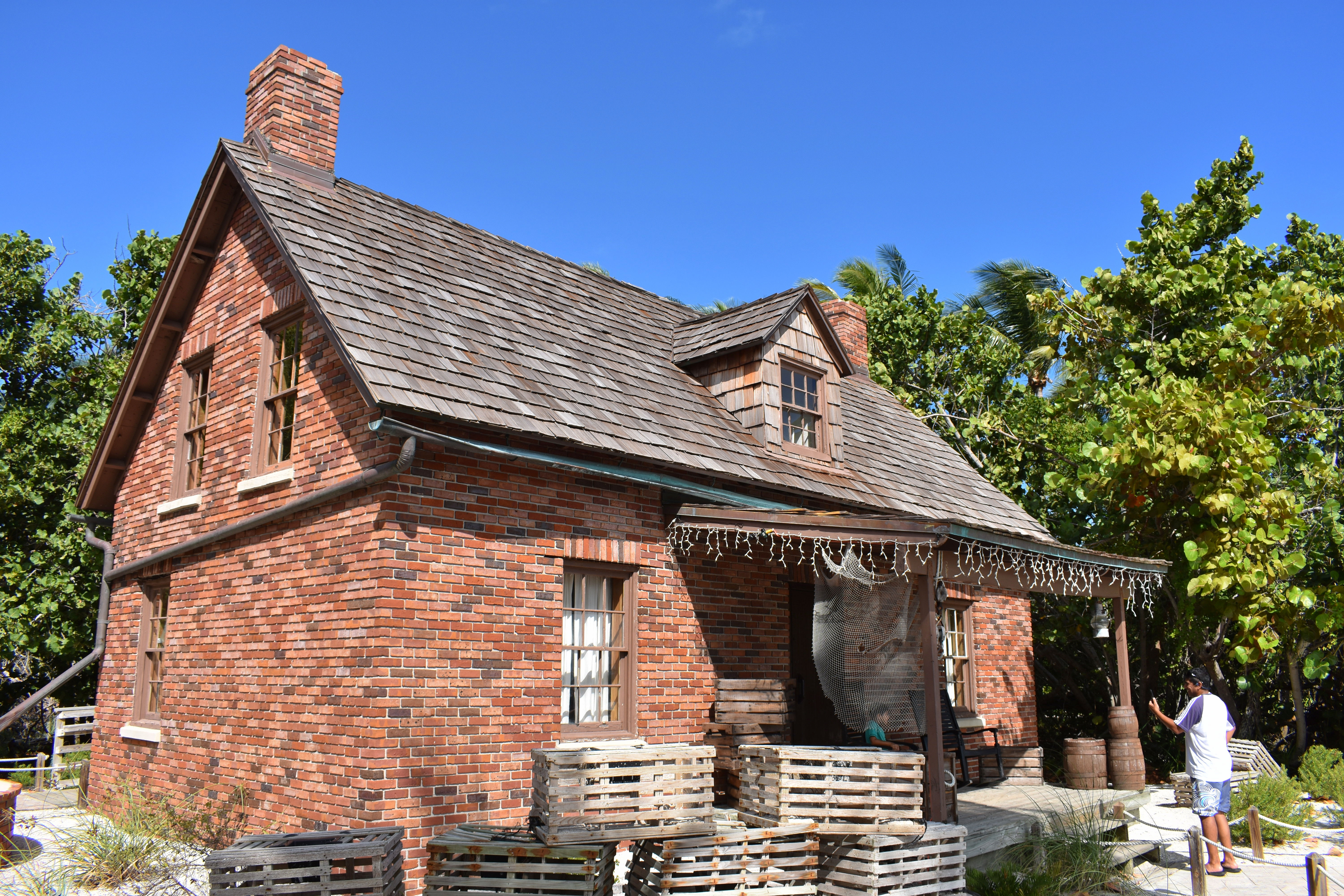 Historic red brick lighthouse keeper's cottage at a Florida state park under a clear blue sky.