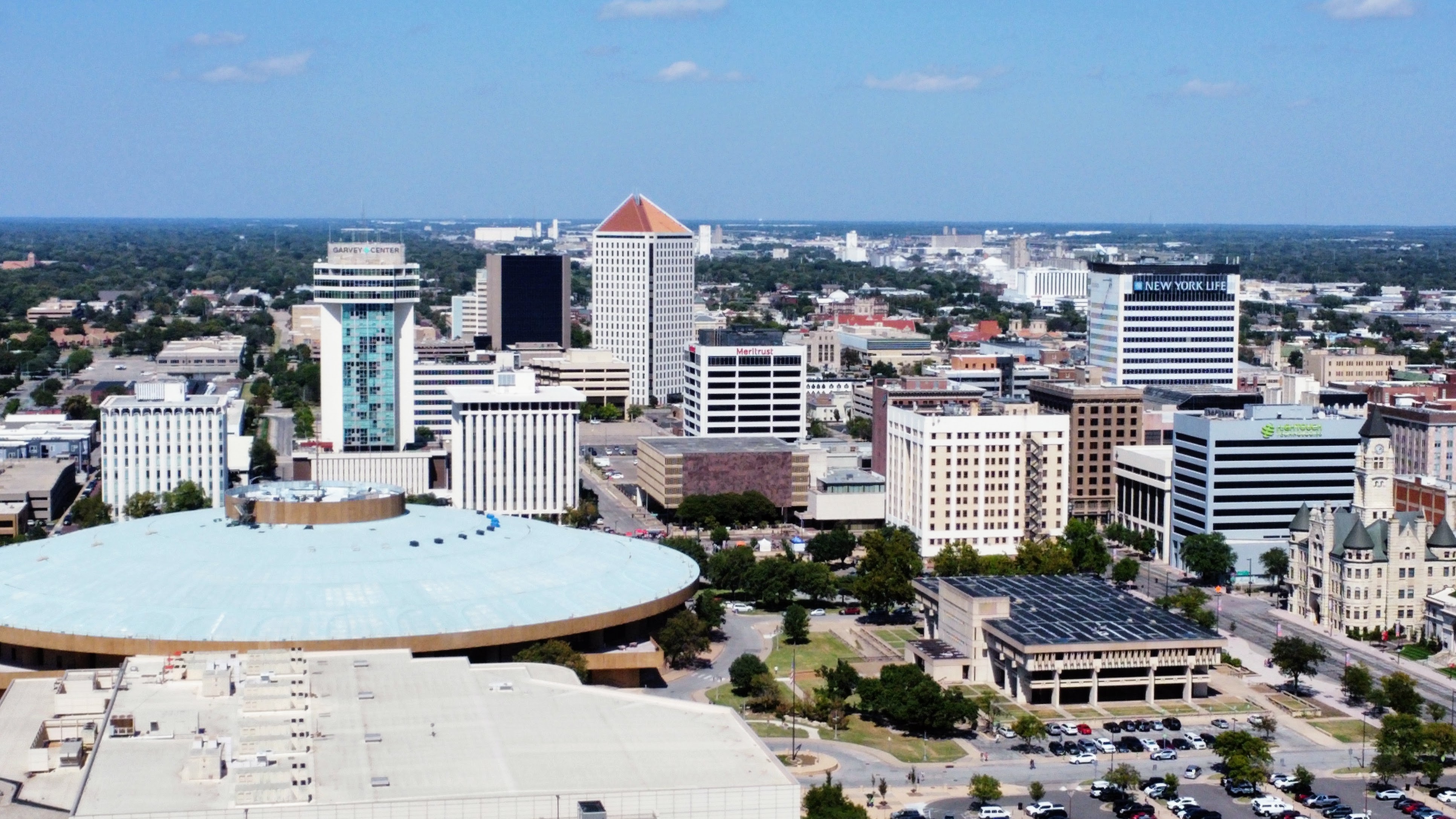 Aerial view of downtown Wichita skyline with circular Century II building in foreground.