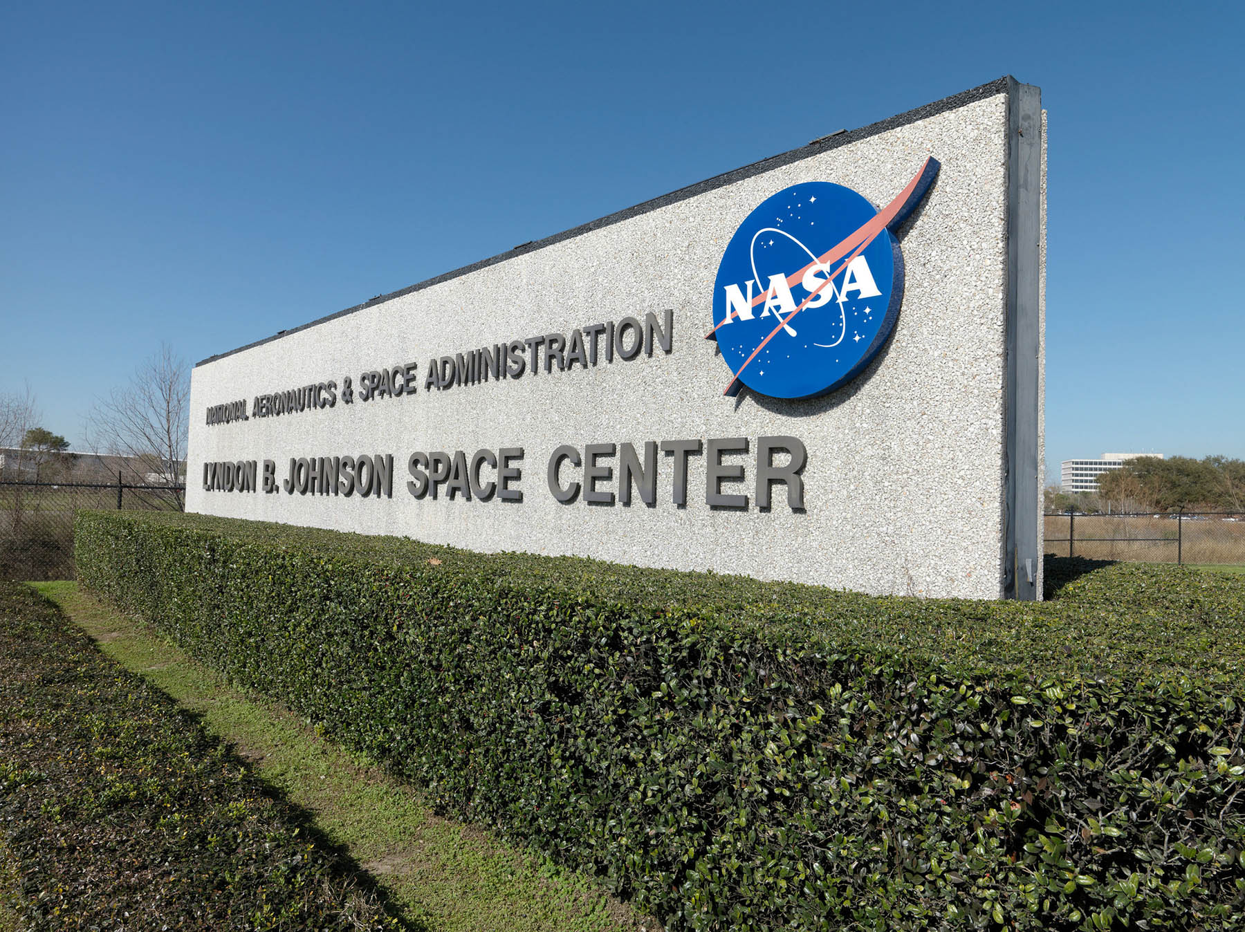 Stone monument sign reading NASA Lyndon B. Johnson Space Center against a blue sky.