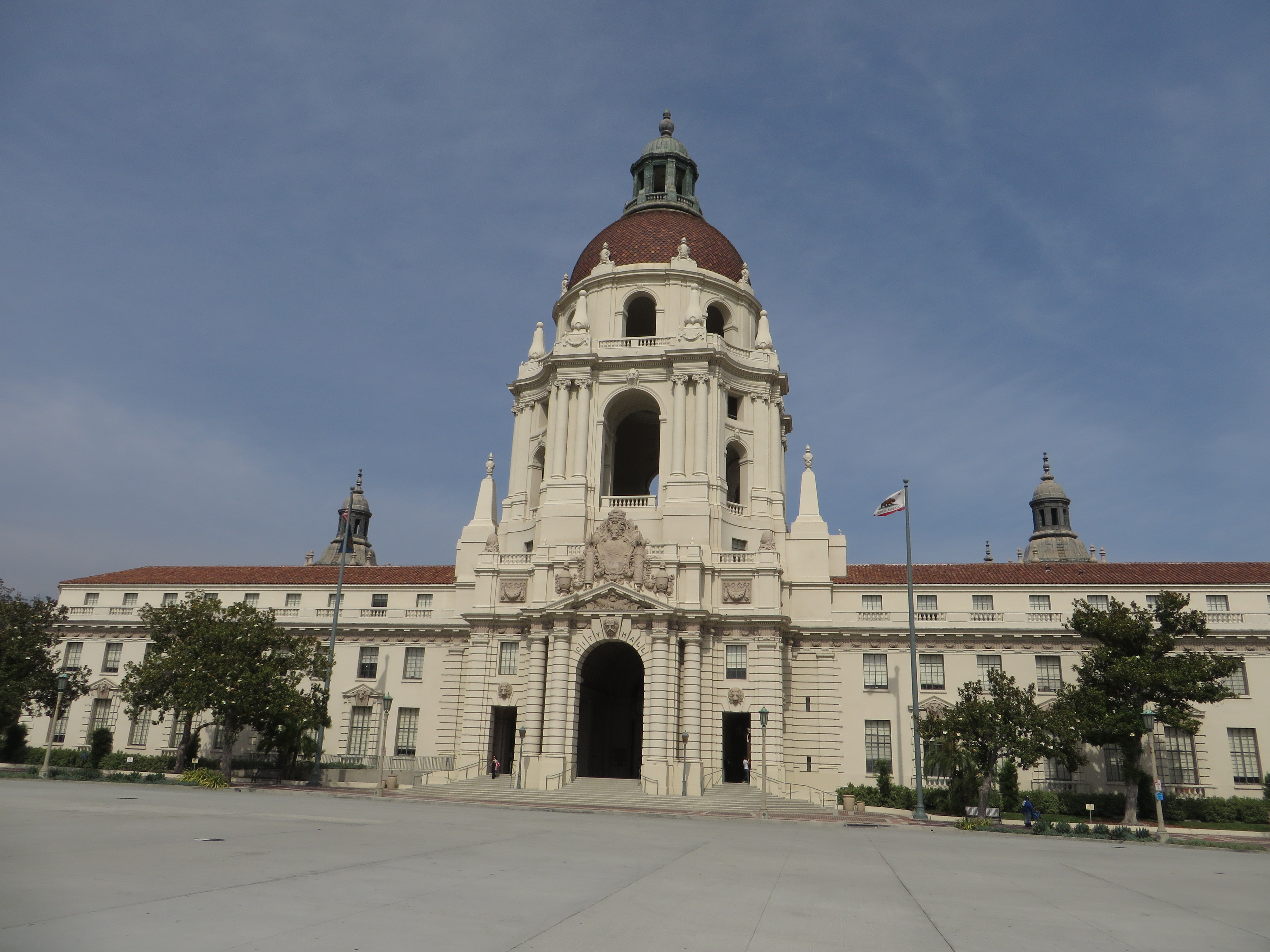 Ornate government building with a large dome and red tile roof under blue sky.
