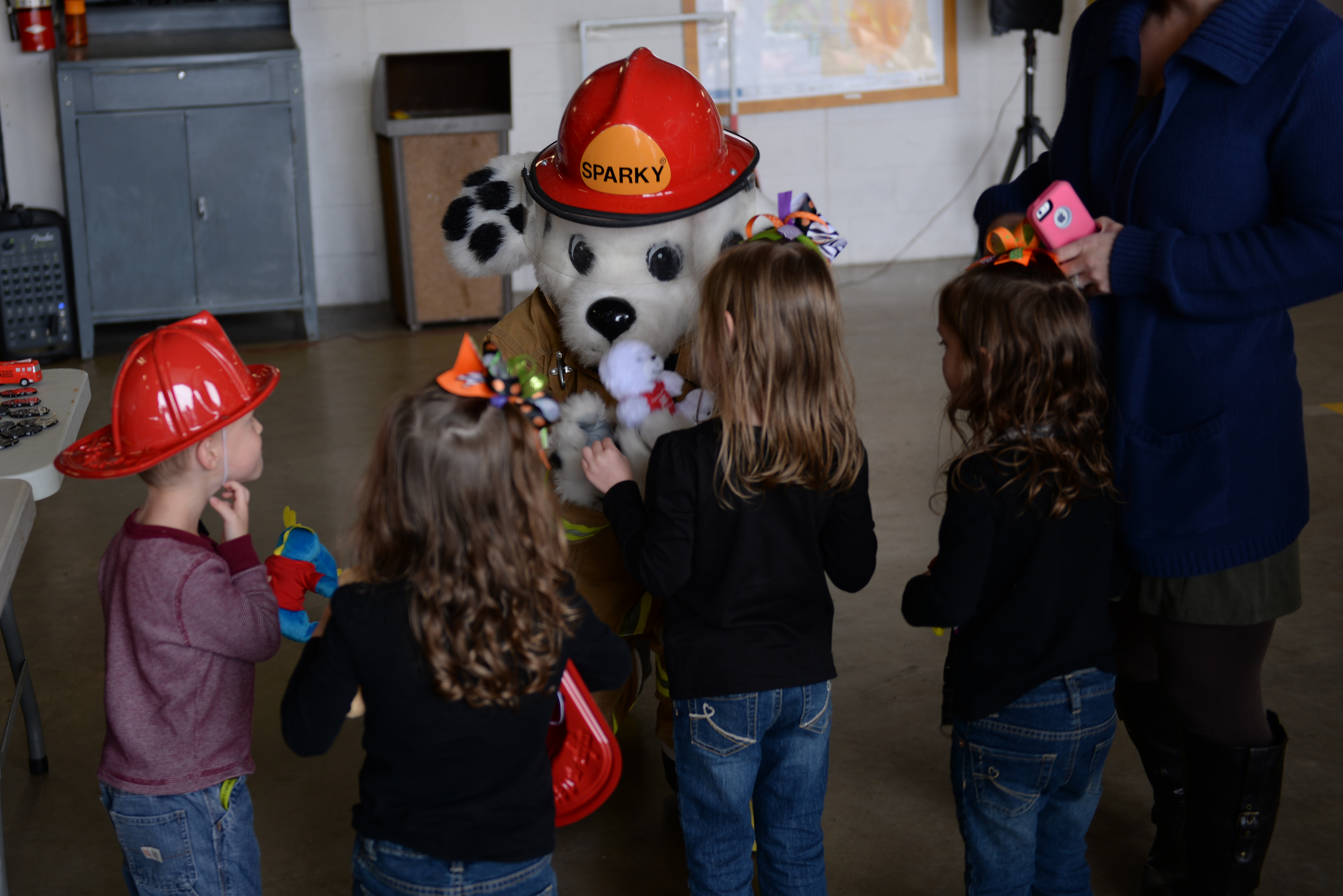 Mascot in Sparky the Fire Dog costume greets young children at a fire station.
