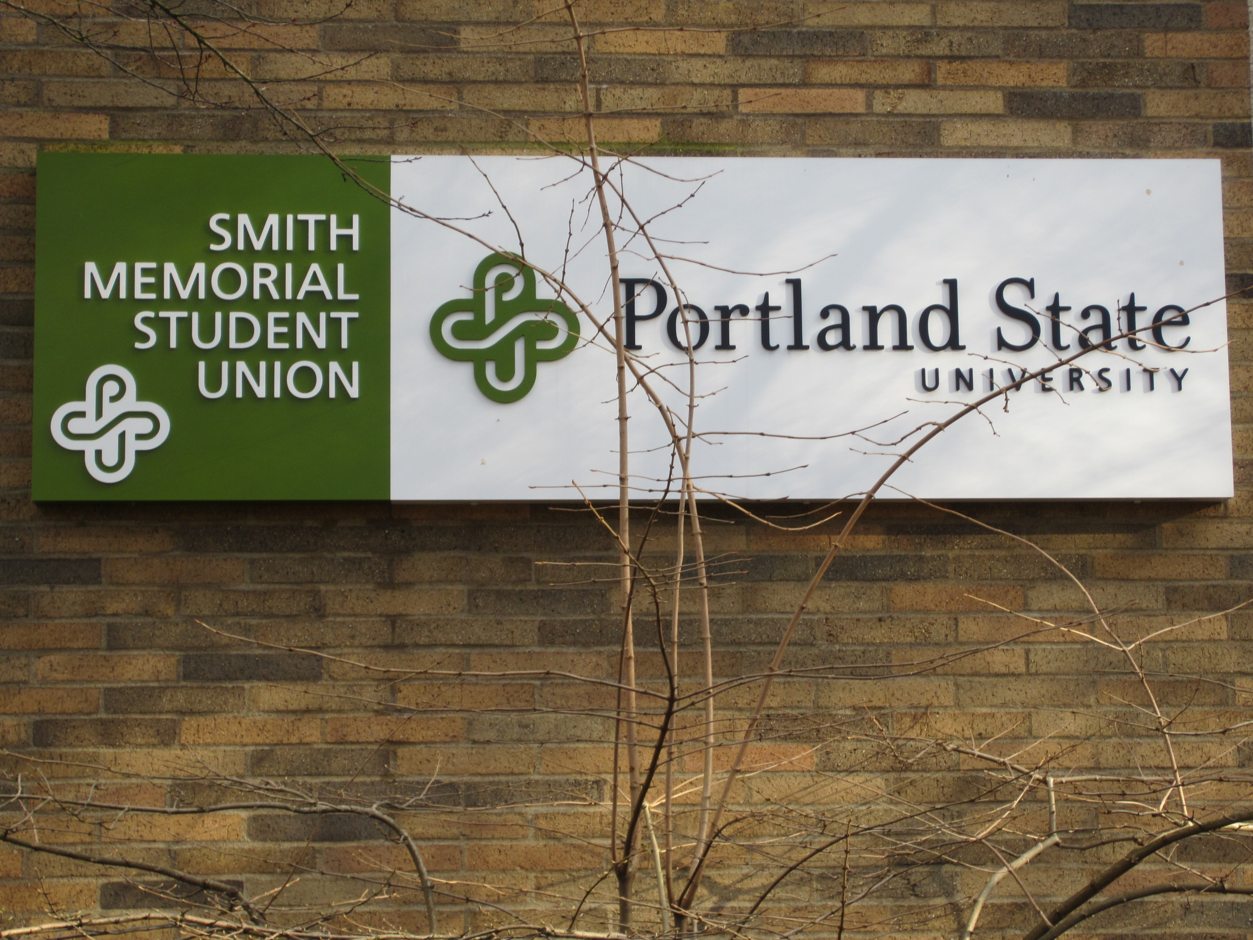 Exterior sign reading 'Portland State University' mounted on a brick wall.