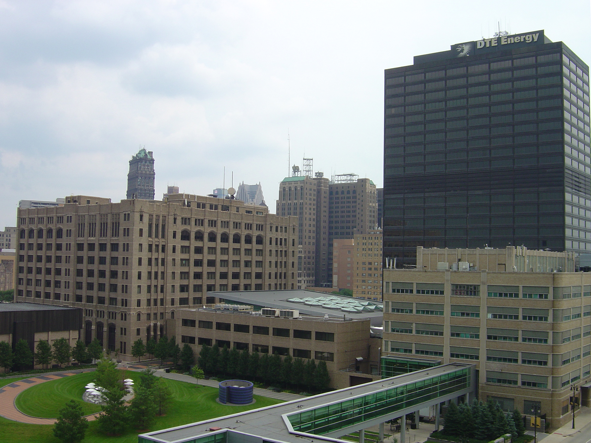 Dark glass high-rise tower with DTE Energy signage at the top, surrounded by downtown buildings.