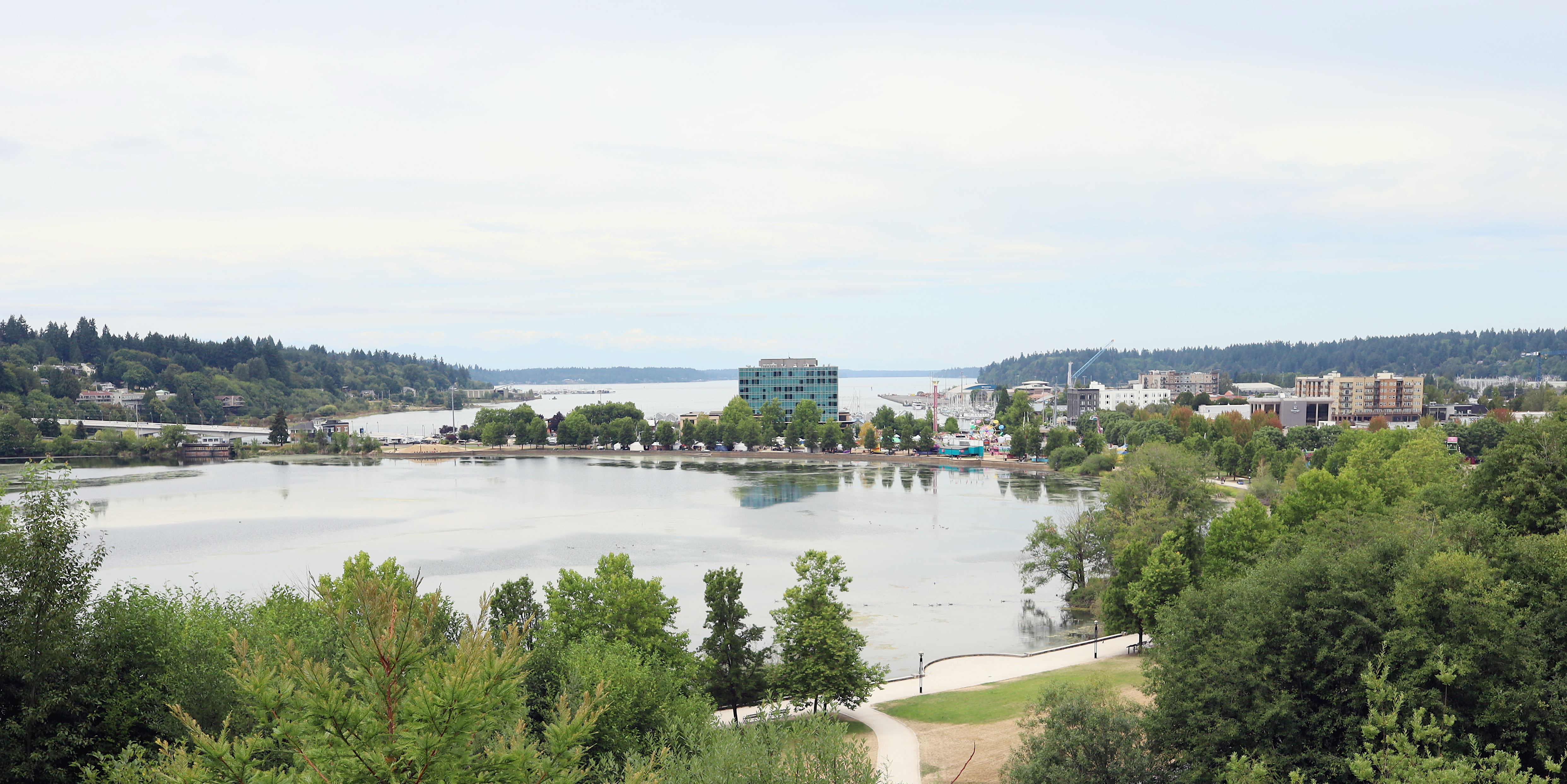 Panoramic view of Capitol Lake with buildings and forested hills across the water.