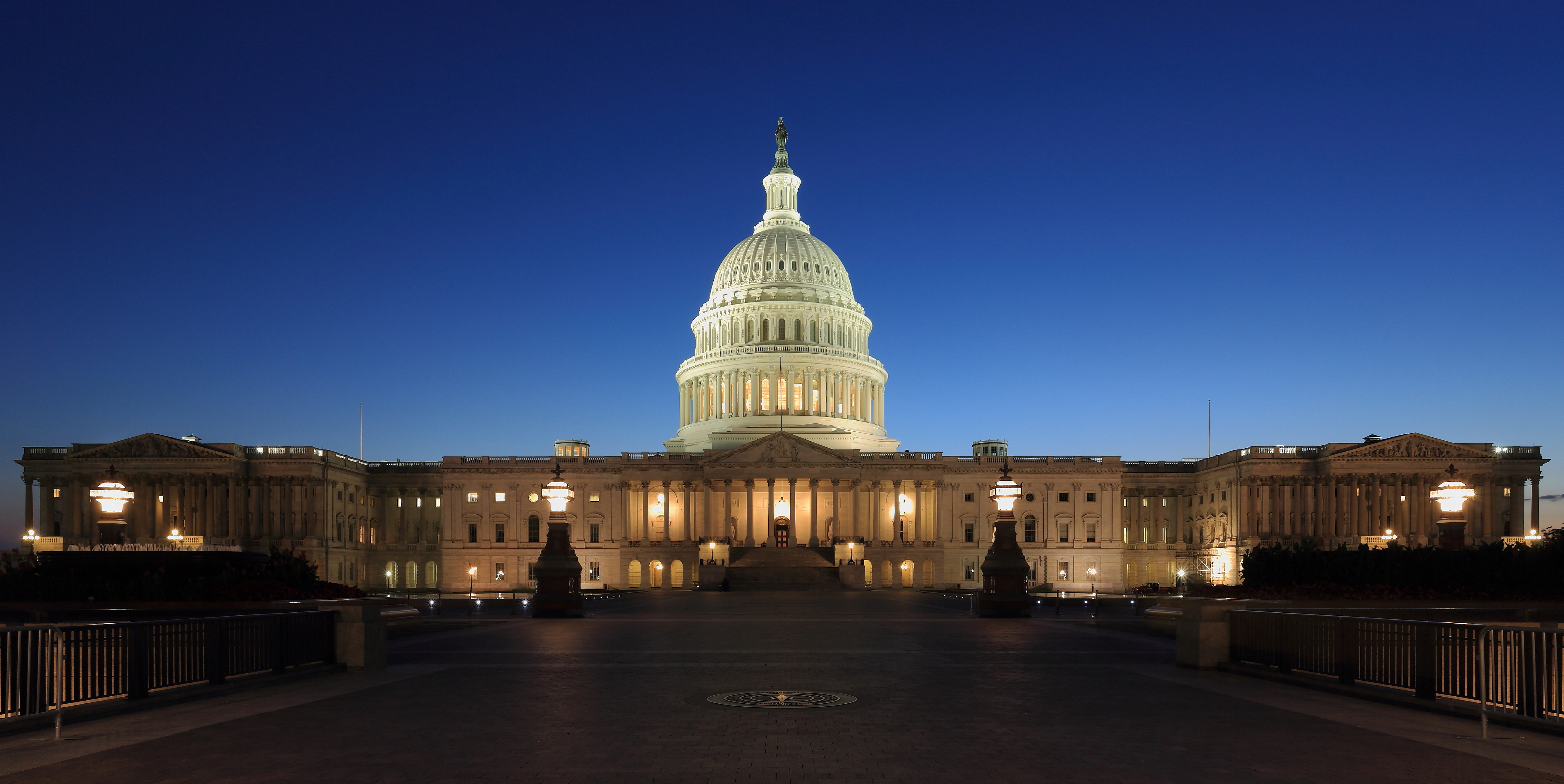The U.S. Capitol building illuminated at dusk against a deep blue sky.