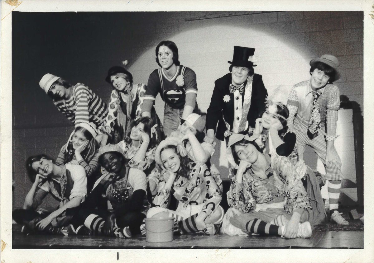 Black-and-white photo of costumed theatrical performers posed together on a stage.