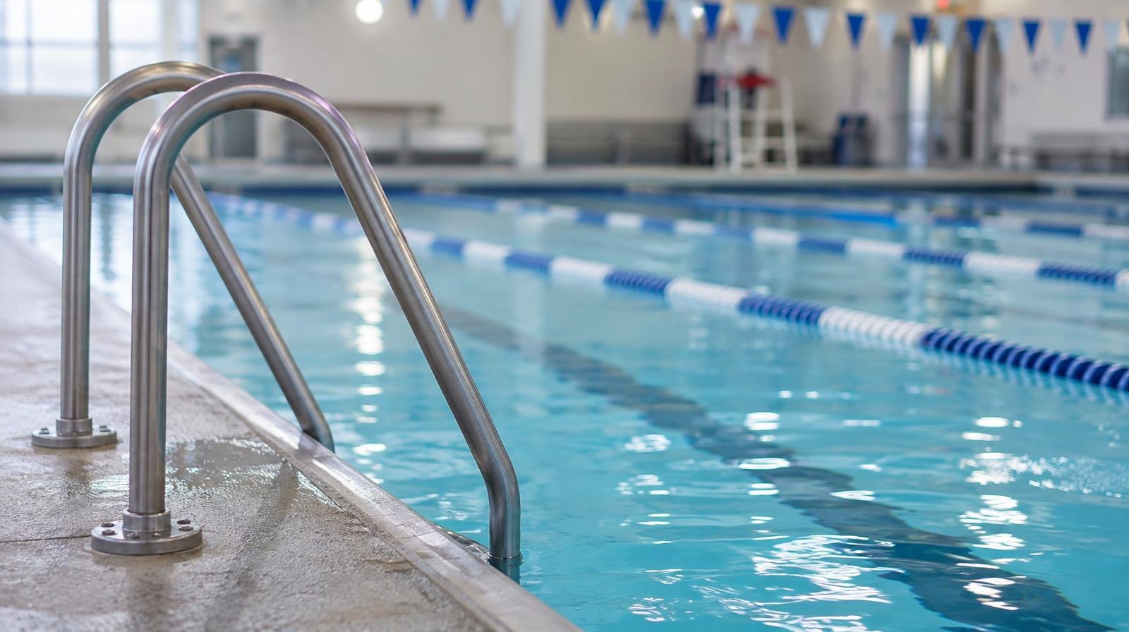 Empty indoor swimming pool with blue lane dividers and tiled walls.