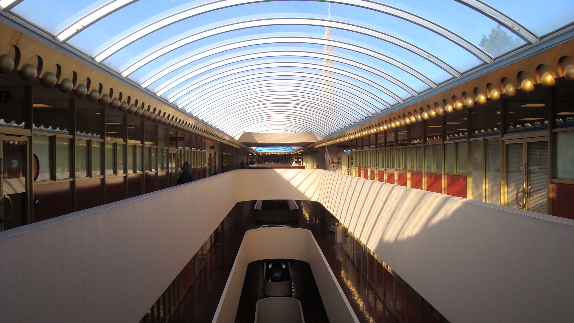 Curved interior corridor with a translucent barrel-vault skylight and two levels of offices.