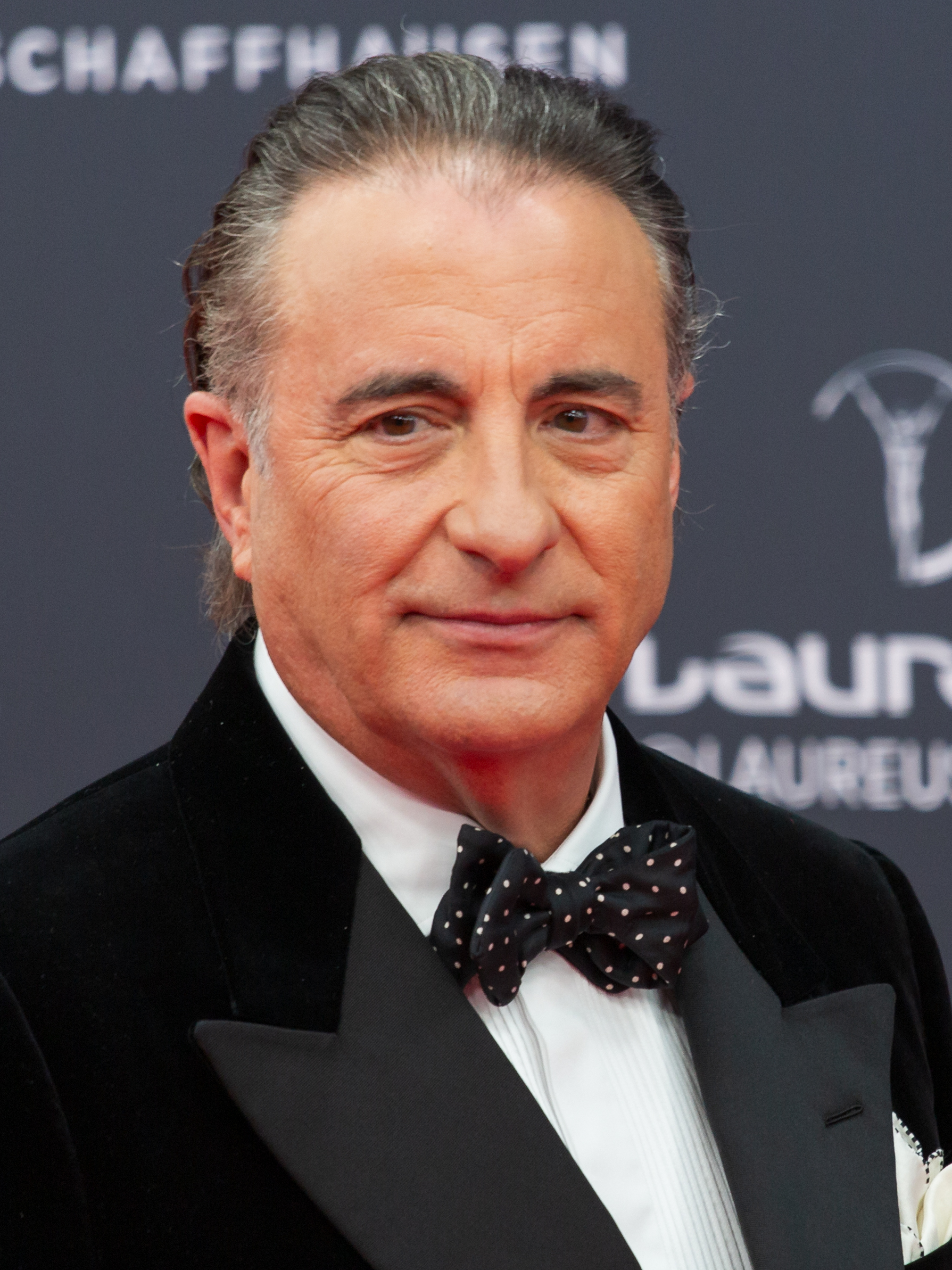 Man in black tuxedo and polka-dot bow tie at a formal awards event.