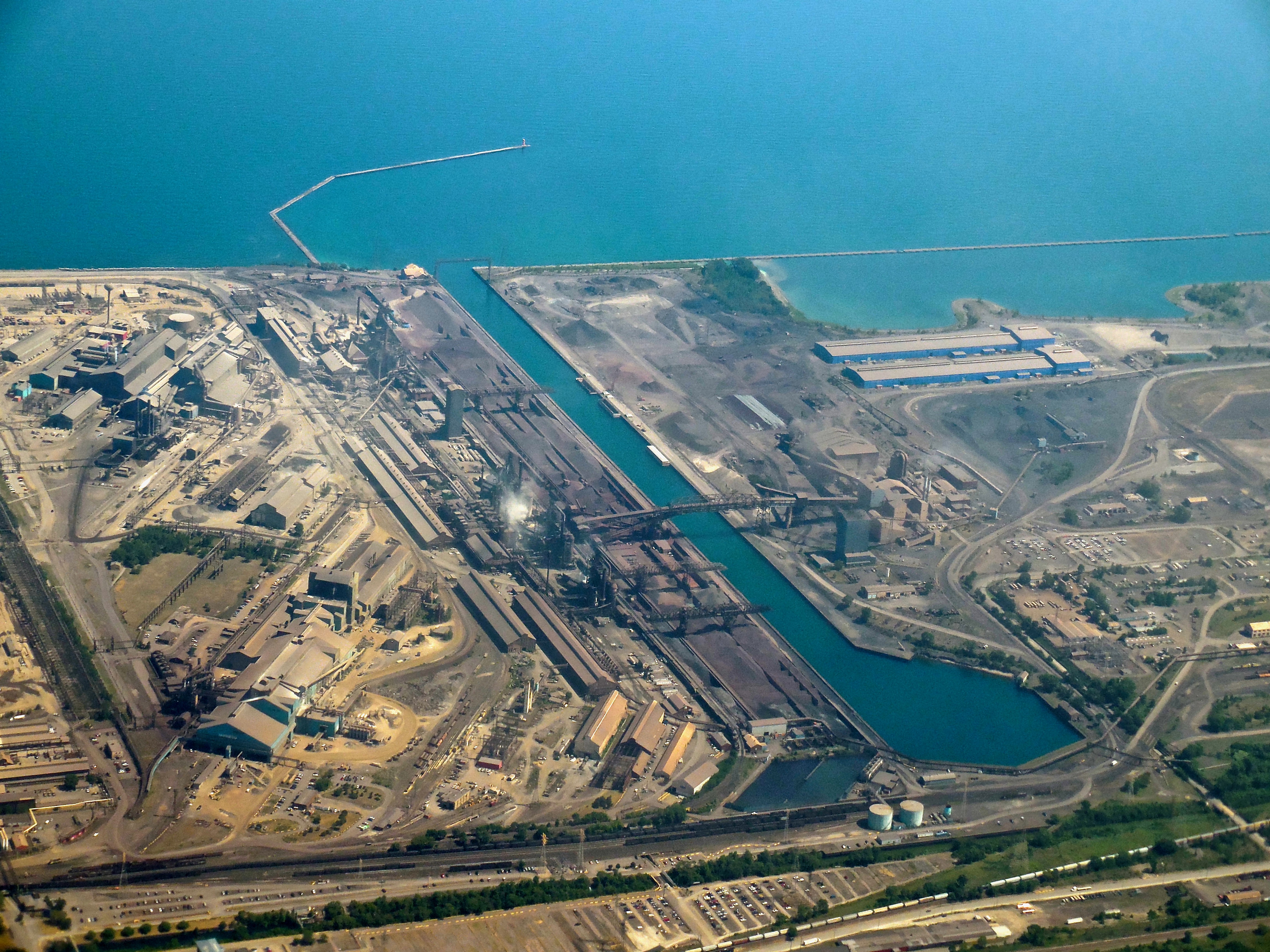 Aerial view of a large industrial steel mill complex along a lakefront.