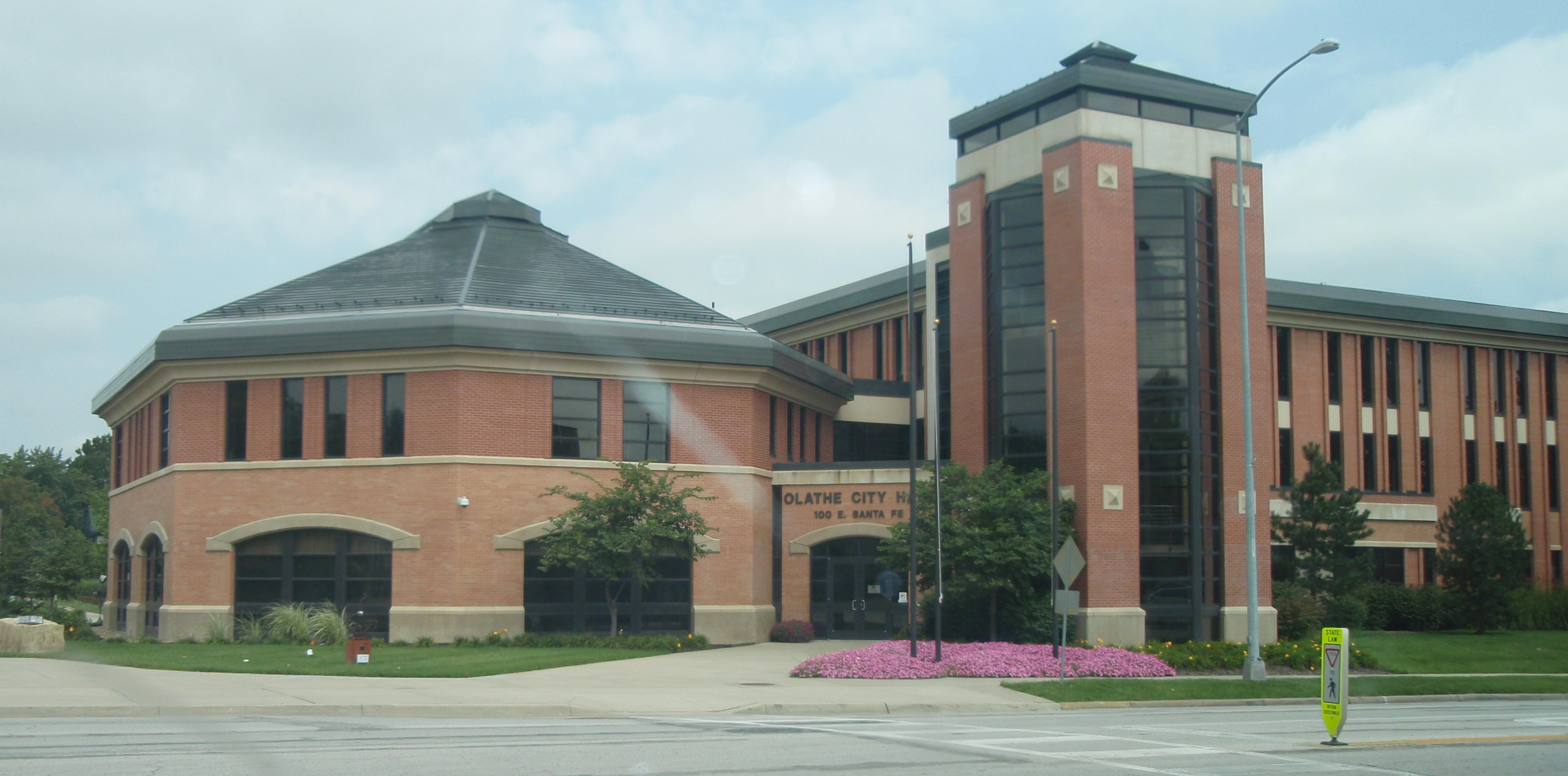 Brick municipal building with circular rotunda and glass tower, labeled Olathe City Hall.