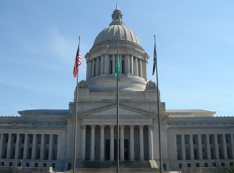 Domed Washington State Capitol Legislative Building with columned entrance and flags flying.