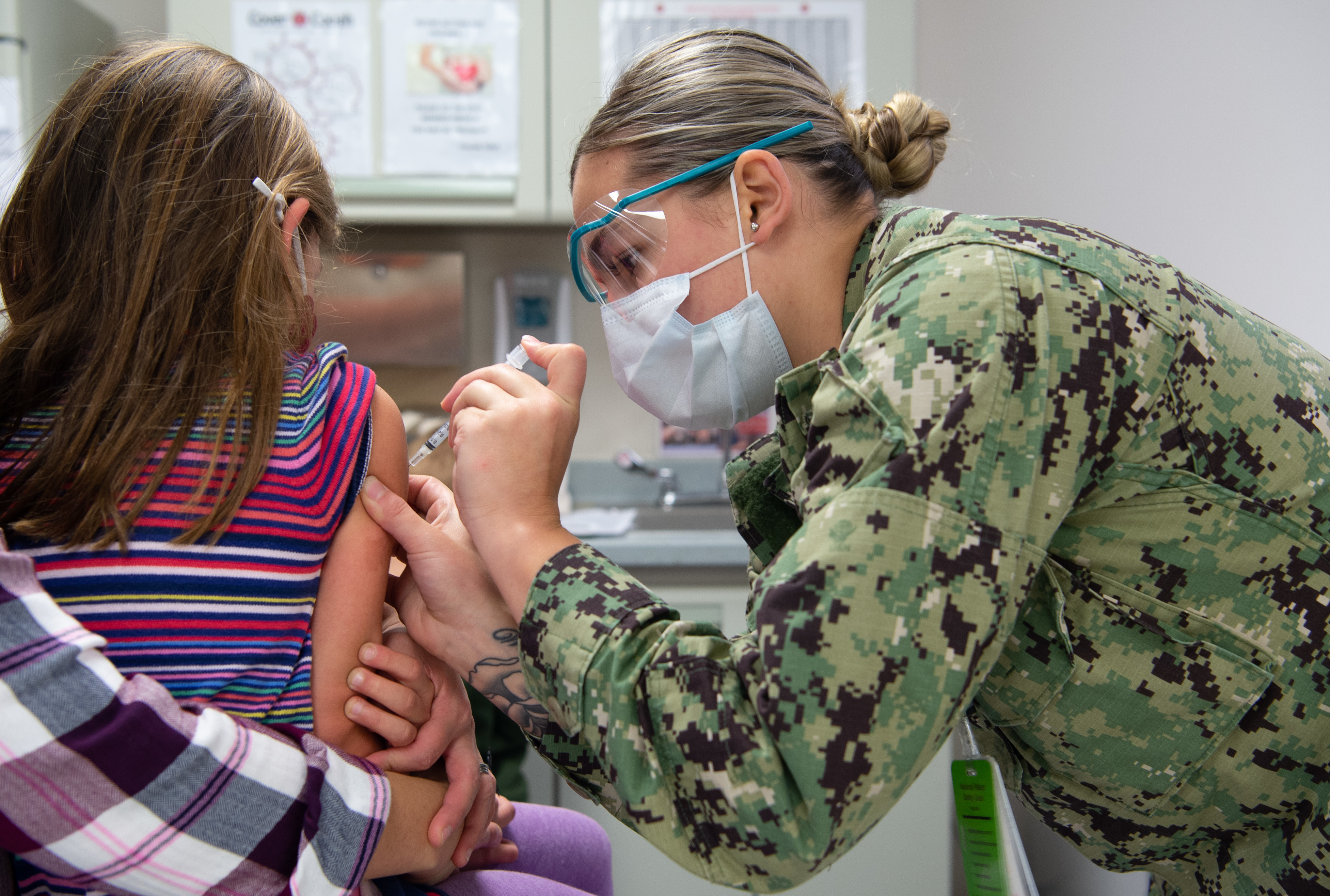 Healthcare worker in uniform giving a vaccine injection to a child's arm.