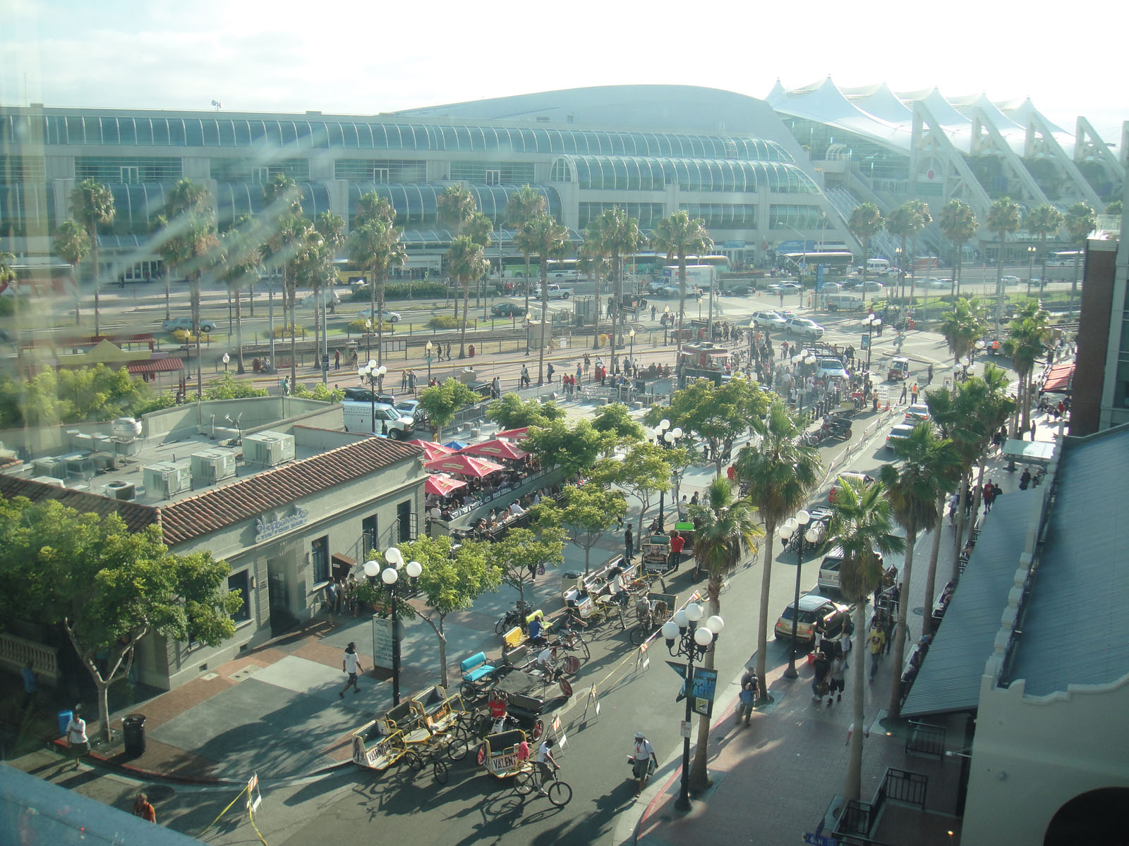 Aerial view of a large convention center with a curved roof surrounded by palm-lined streets.