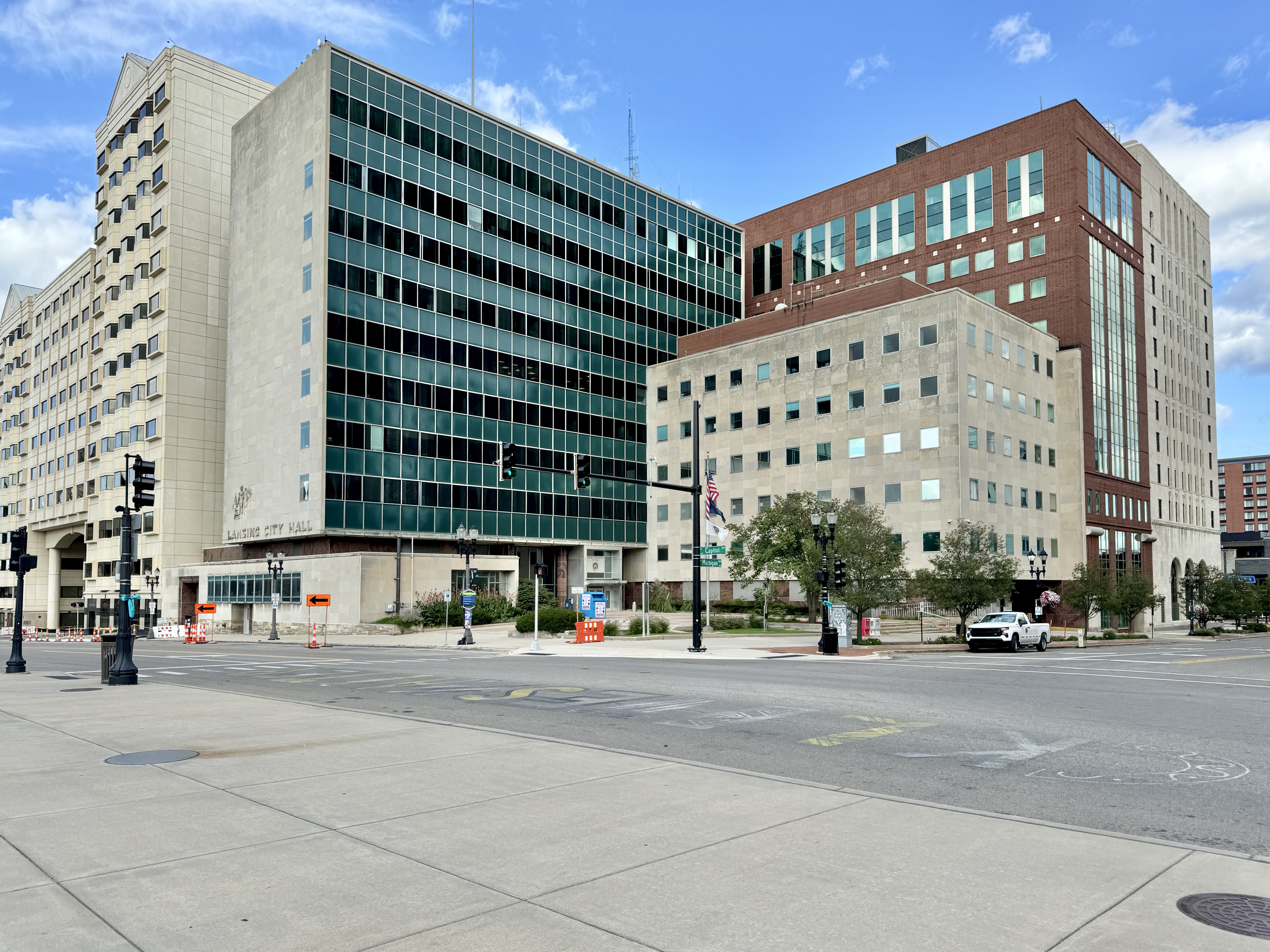 Multi-story glass and limestone government building at a downtown street intersection.