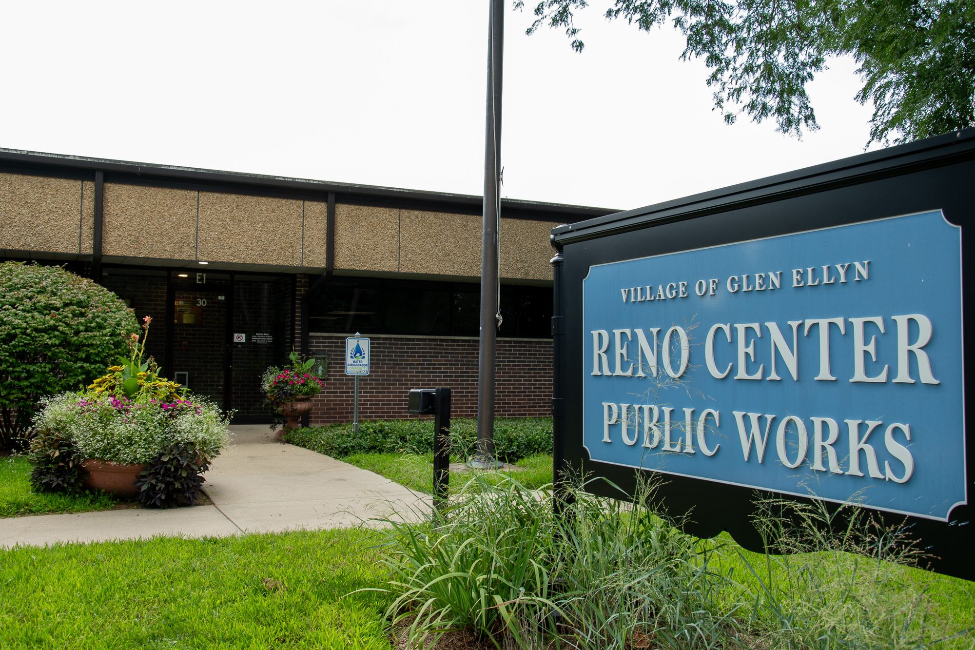 Sign and exterior of a public works facility in front of a brick building.
