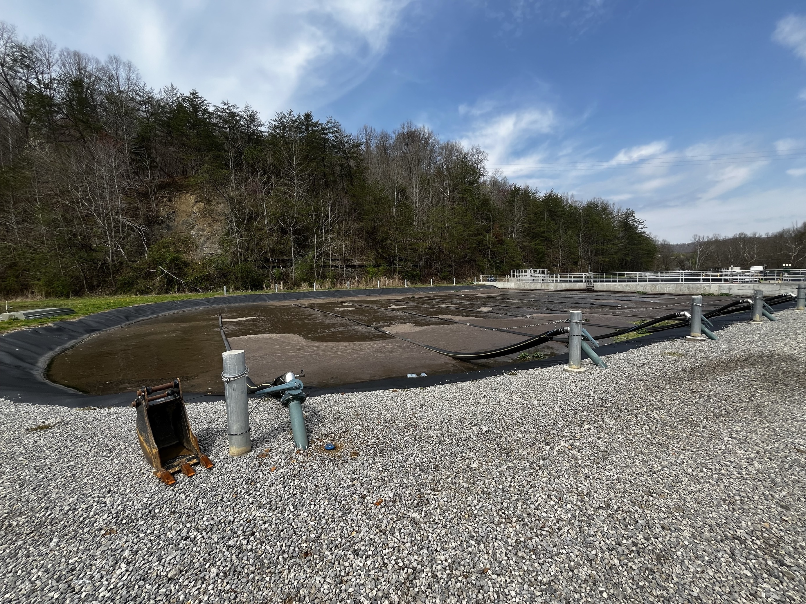 A lined wastewater treatment pond with metal standpipes and gravel surroundings at an Ohio facility.