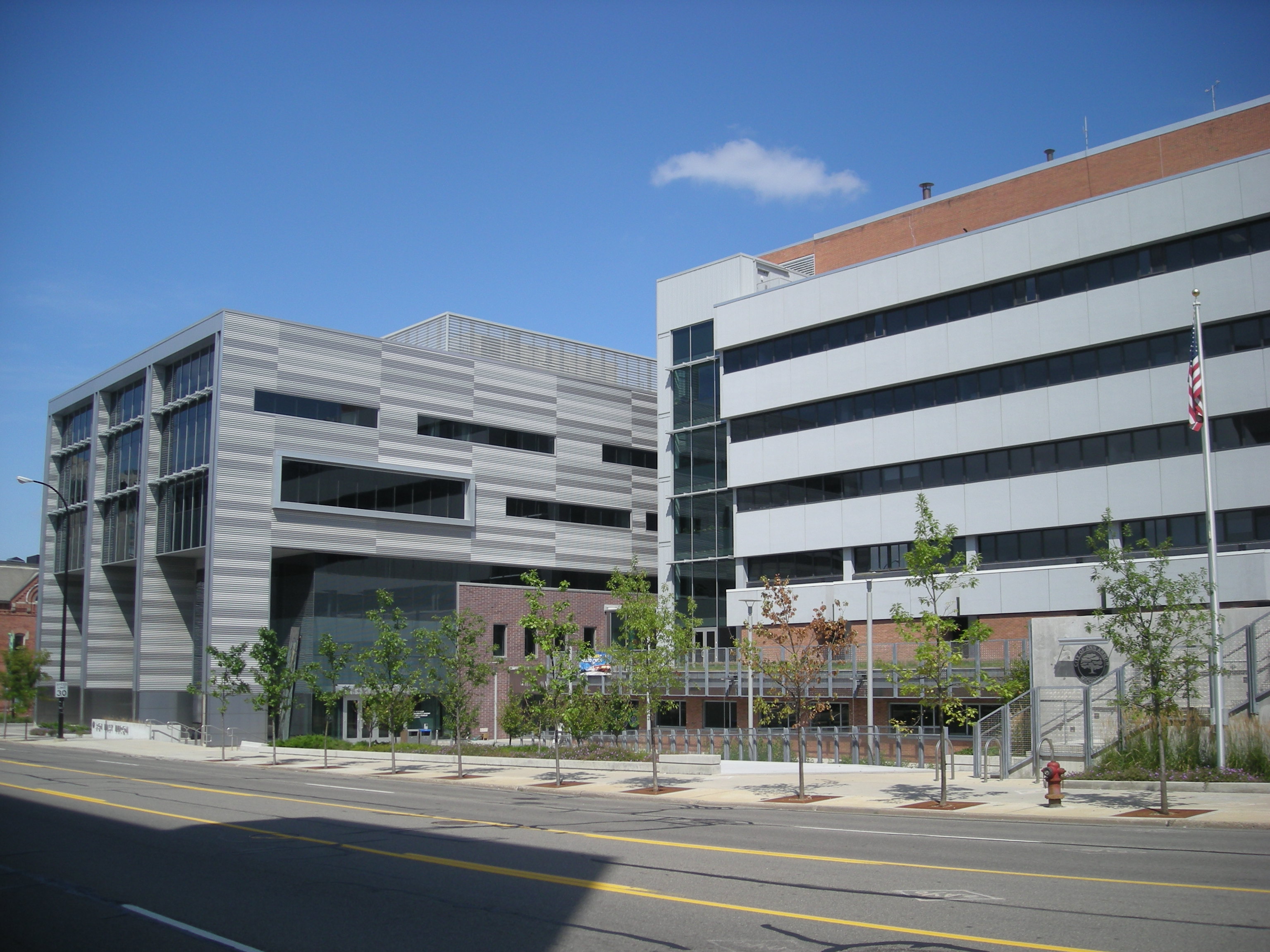 Two modern gray municipal buildings with an American flag on a flagpole out front.