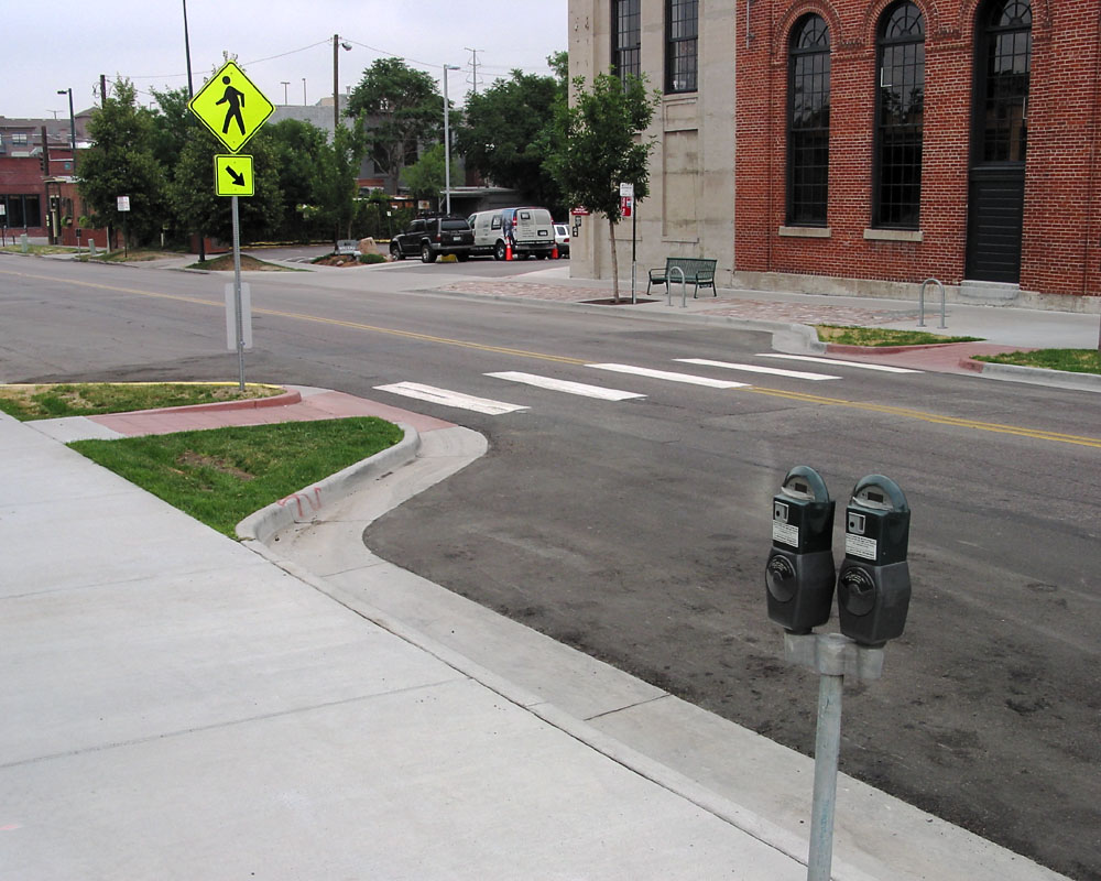 Curb extensions and ADA ramps at a marked midblock crosswalk with a pedestrian crossing sign.