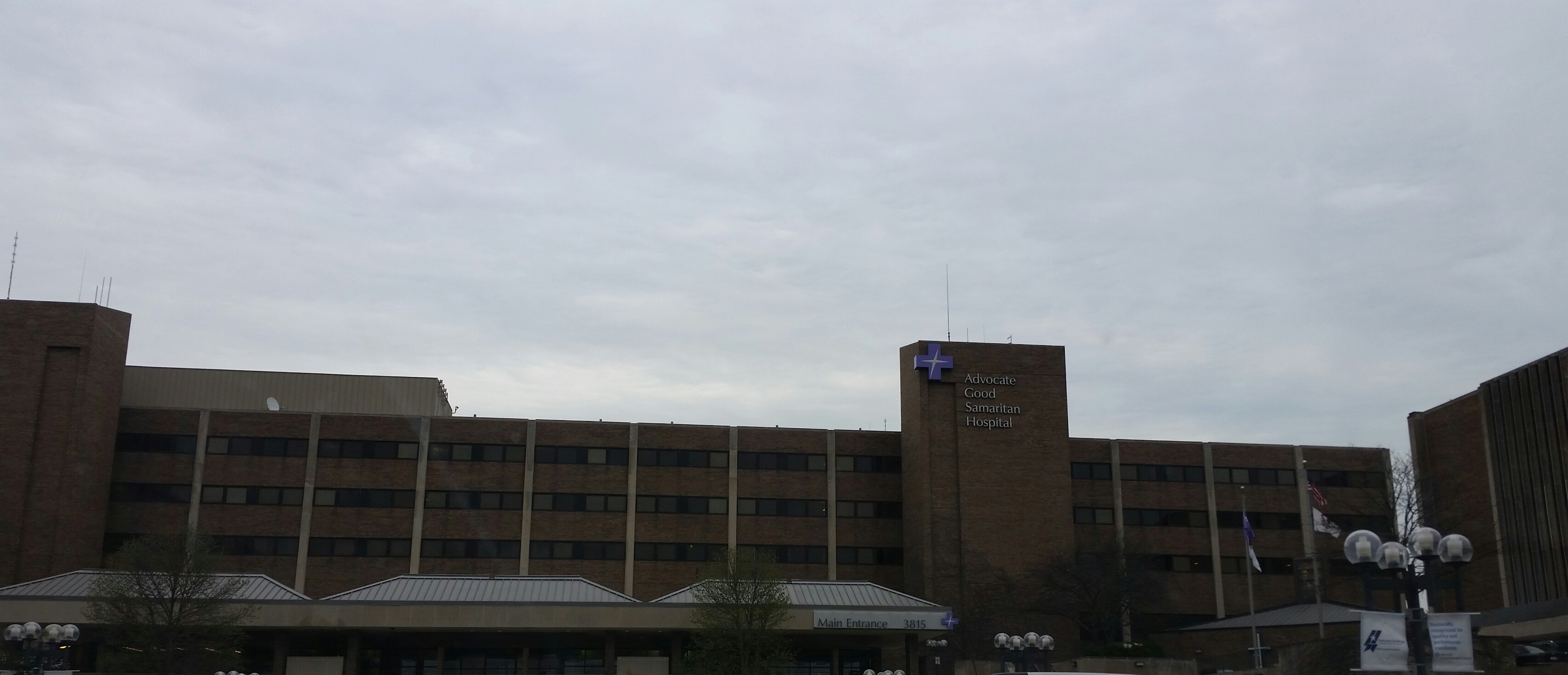 Multi-story brick hospital building with a covered entrance canopy and flagpoles.