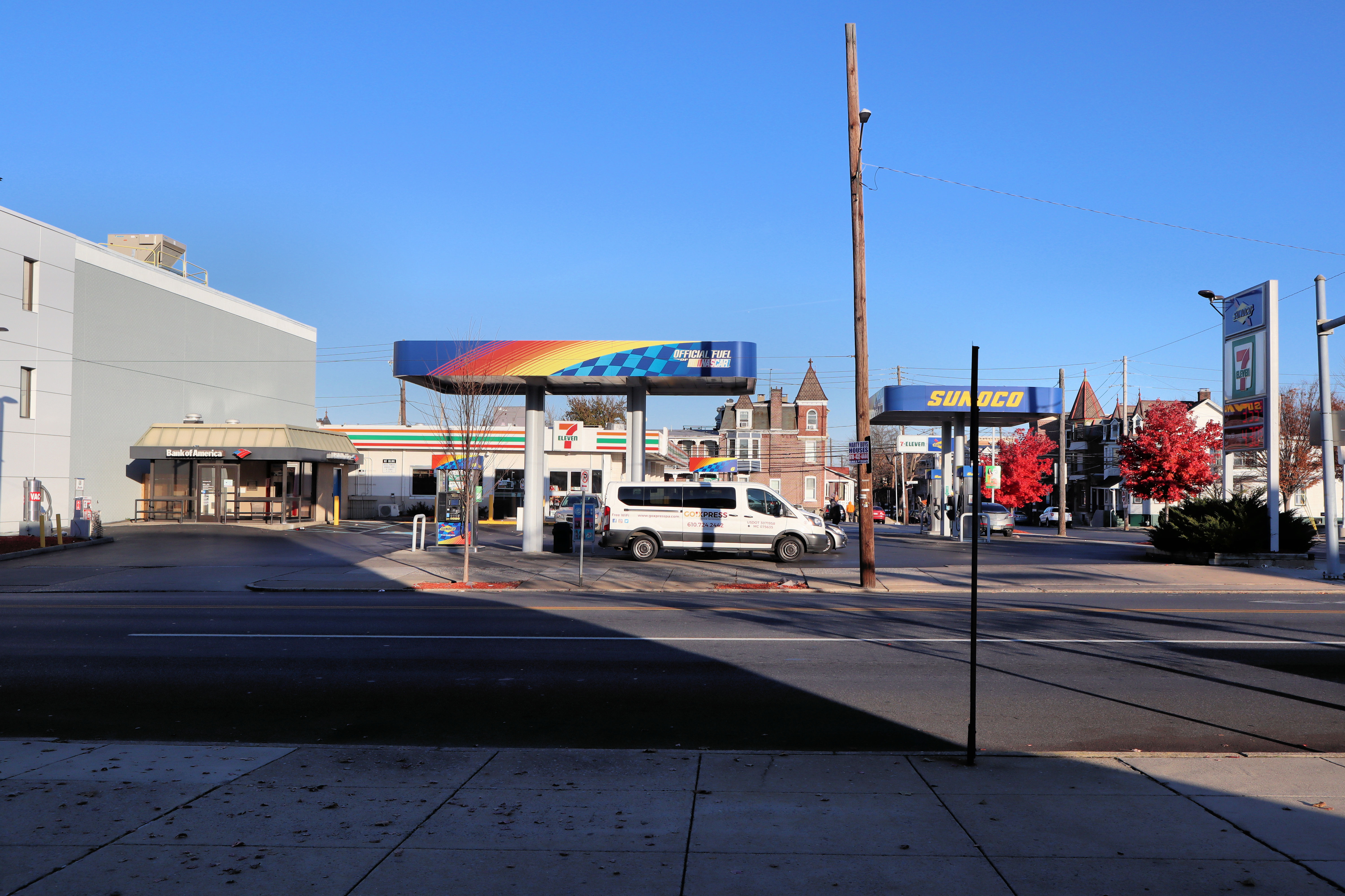 Convenience store and gas station at a street corner with a white van under the fuel canopy.