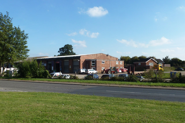 Low-rise brick commercial building with vehicles and equipment parked in front.
