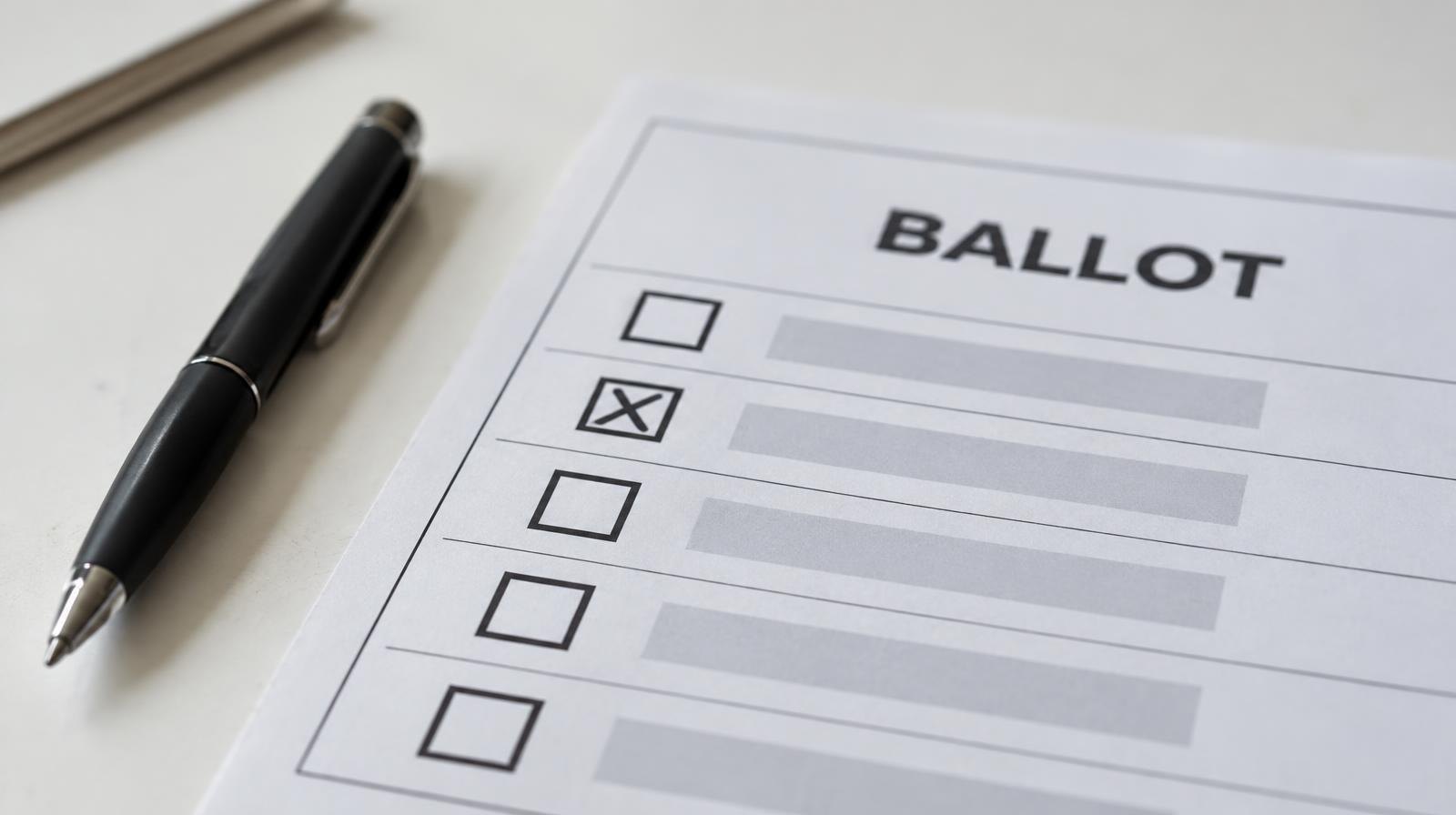 A paper ballot resting on a surface next to a black ink pen.