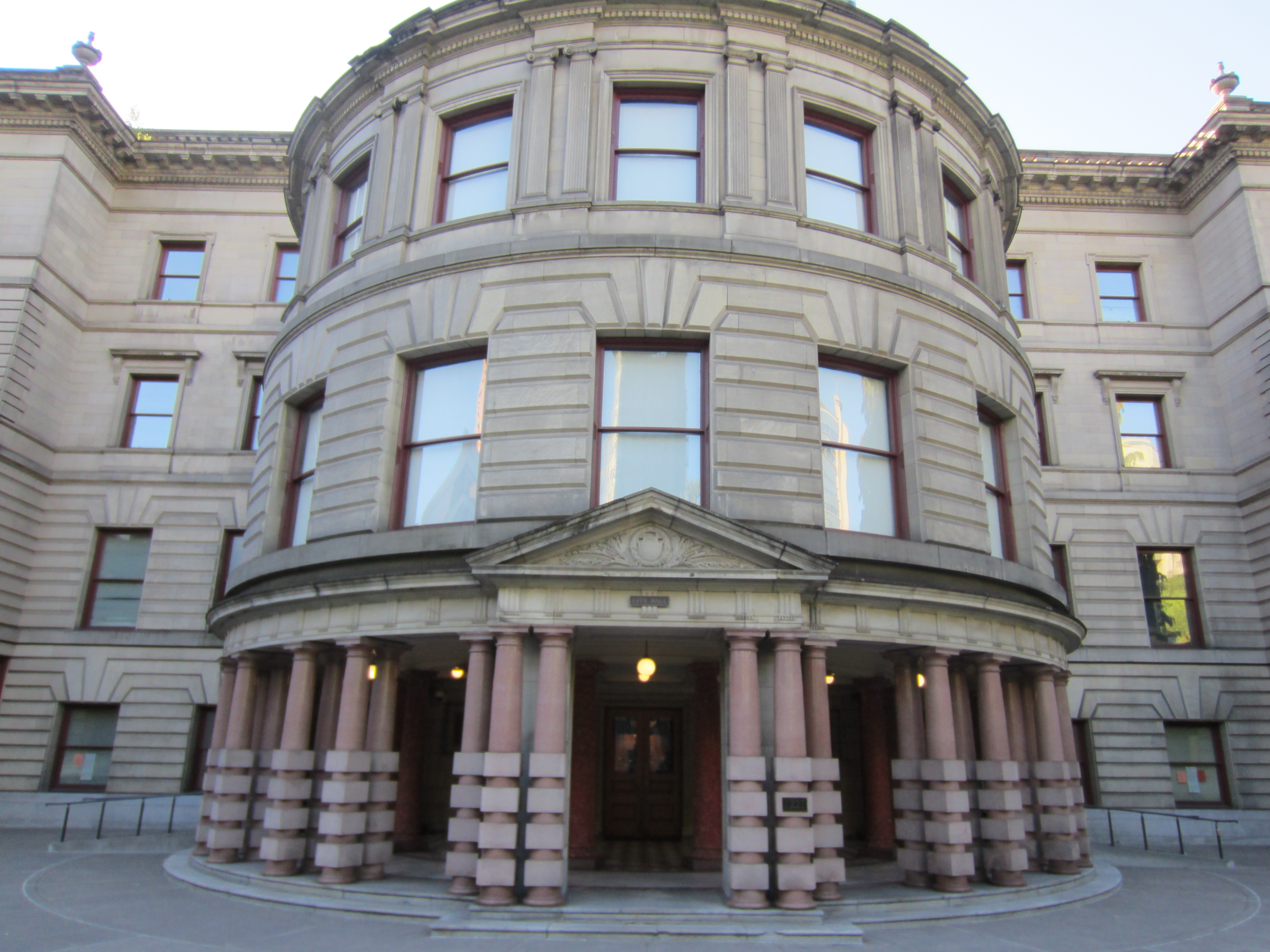 Neoclassical building entrance with pink granite columns and stone pediment.